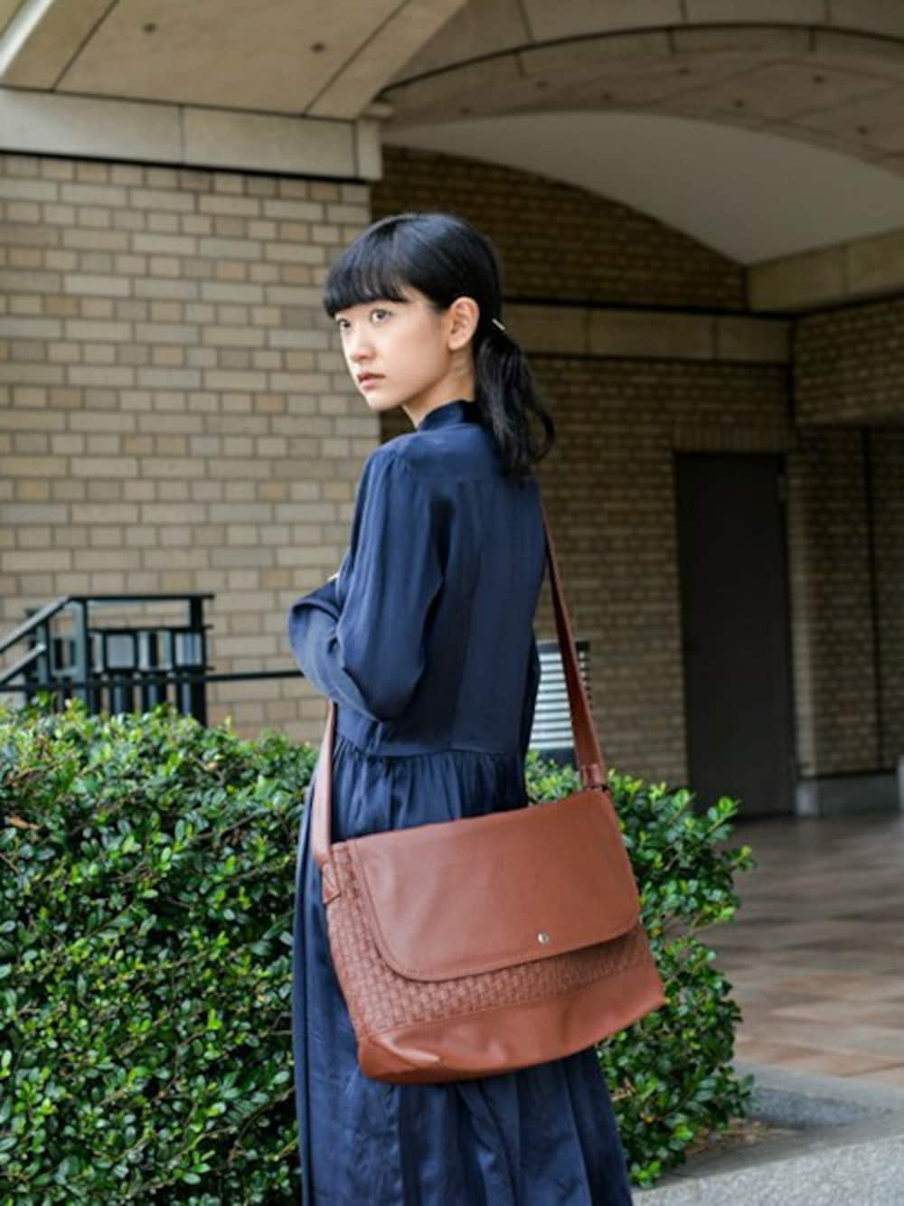 ブラウン系のメッセンジャーバッグを着用したレディースの冬コーディネートの1枚目の写真