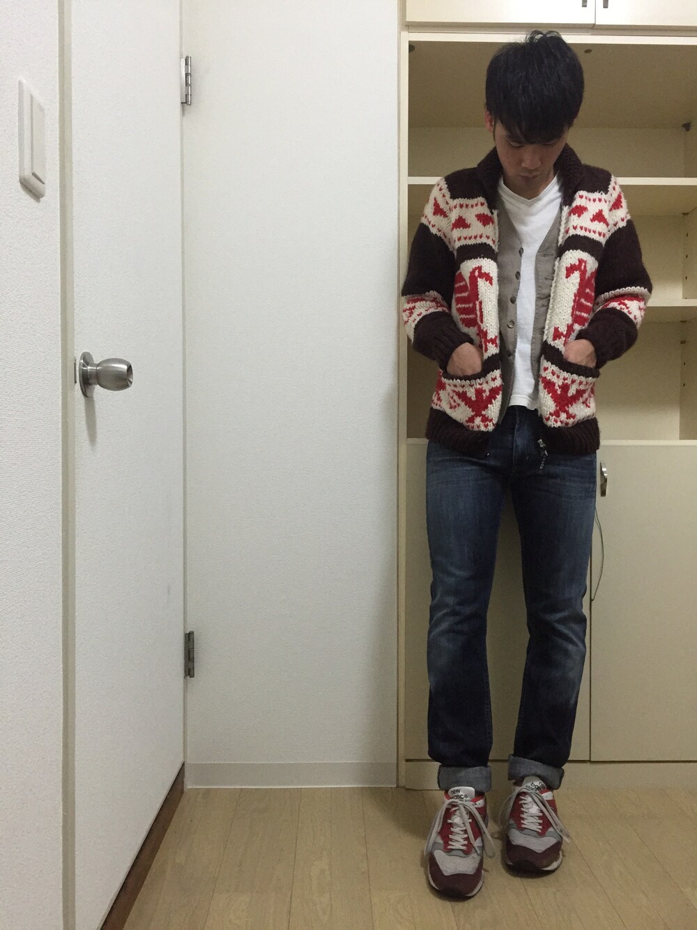 レッド系のニット/セーター、ブラウン系のベスト、ホワイト系のTシャツ/カットソーを着用したメンズの秋コーディネートの1枚目の写真