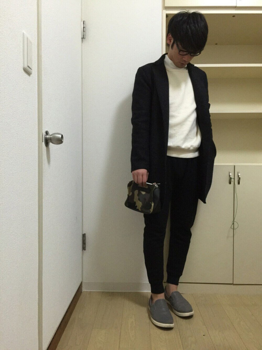 ブラック系のチェスターコート、ホワイト系のスウェット、ホワイト系のTシャツ/カットソーを着用したメンズの冬コーディネートの1枚目の写真