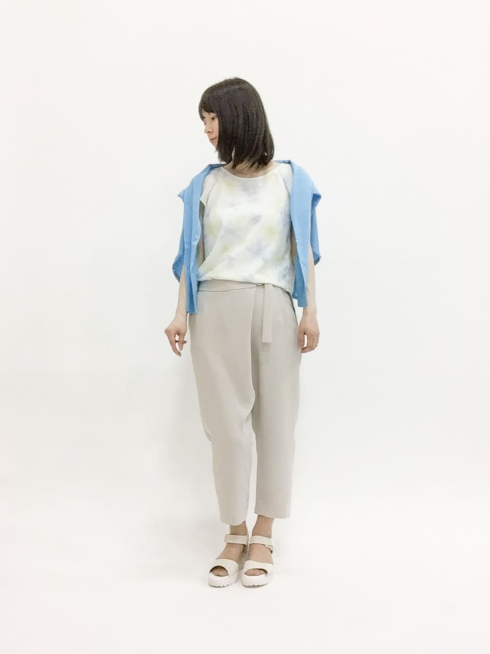 ブルー系のニット/セーター、イエロー系のシャツ/ブラウス、ベージュ系のその他パンツを着用したレディースの春コーディネートの1枚目の写真