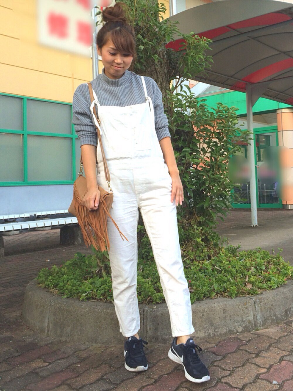 グレー系のトップス、ホワイト系のサロペット/オーバーオール、ブラウン系のショルダーバッグを着用したレディースの秋コーディネートの1枚目の写真