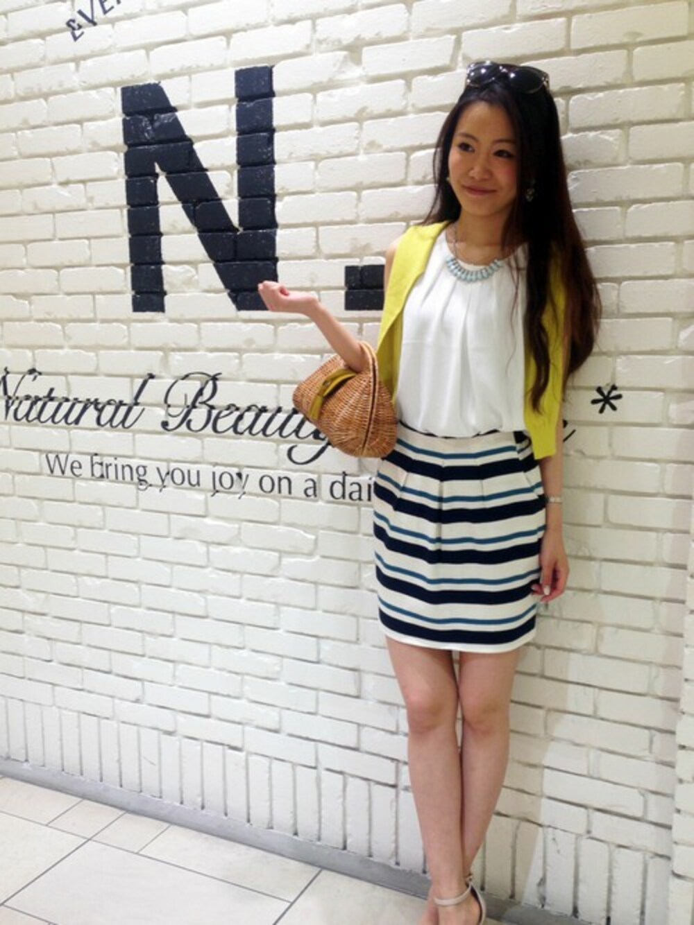 ブルー系のスカート、イエロー系のカーディガン/ボレロを着用したレディースの夏コーディネートの1枚目の写真