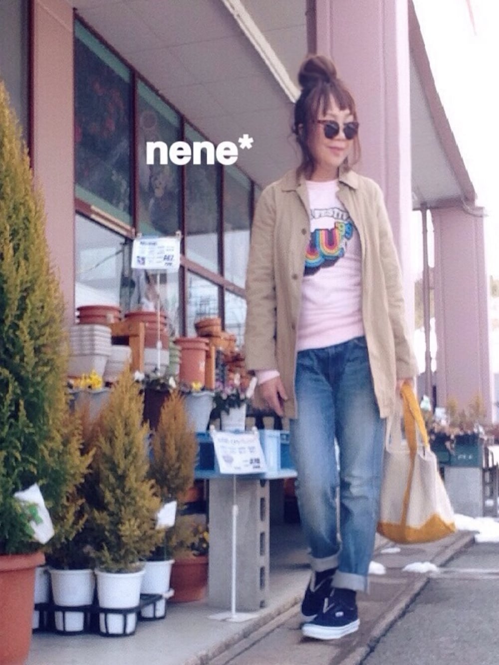 ベージュ系のステンカラーコート、ブルー系のデニムパンツ、ホワイト系のトートバッグを着用したレディースの冬コーディネートの1枚目の写真