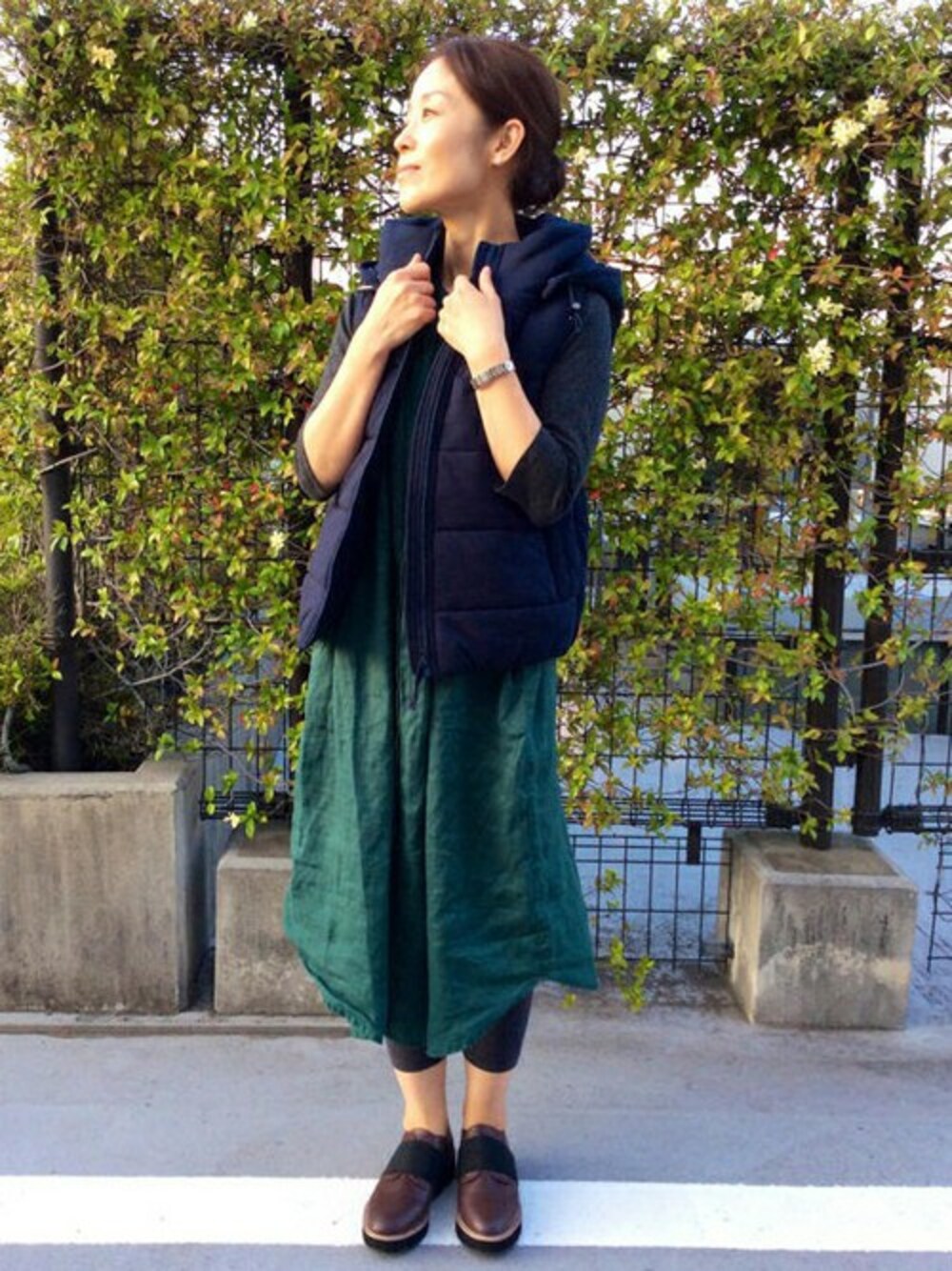 グレー系のTシャツ/カットソー、ブルー系のダウンベスト、グリーン系のワンピースを着用したレディースの秋コーディネートの1枚目の写真