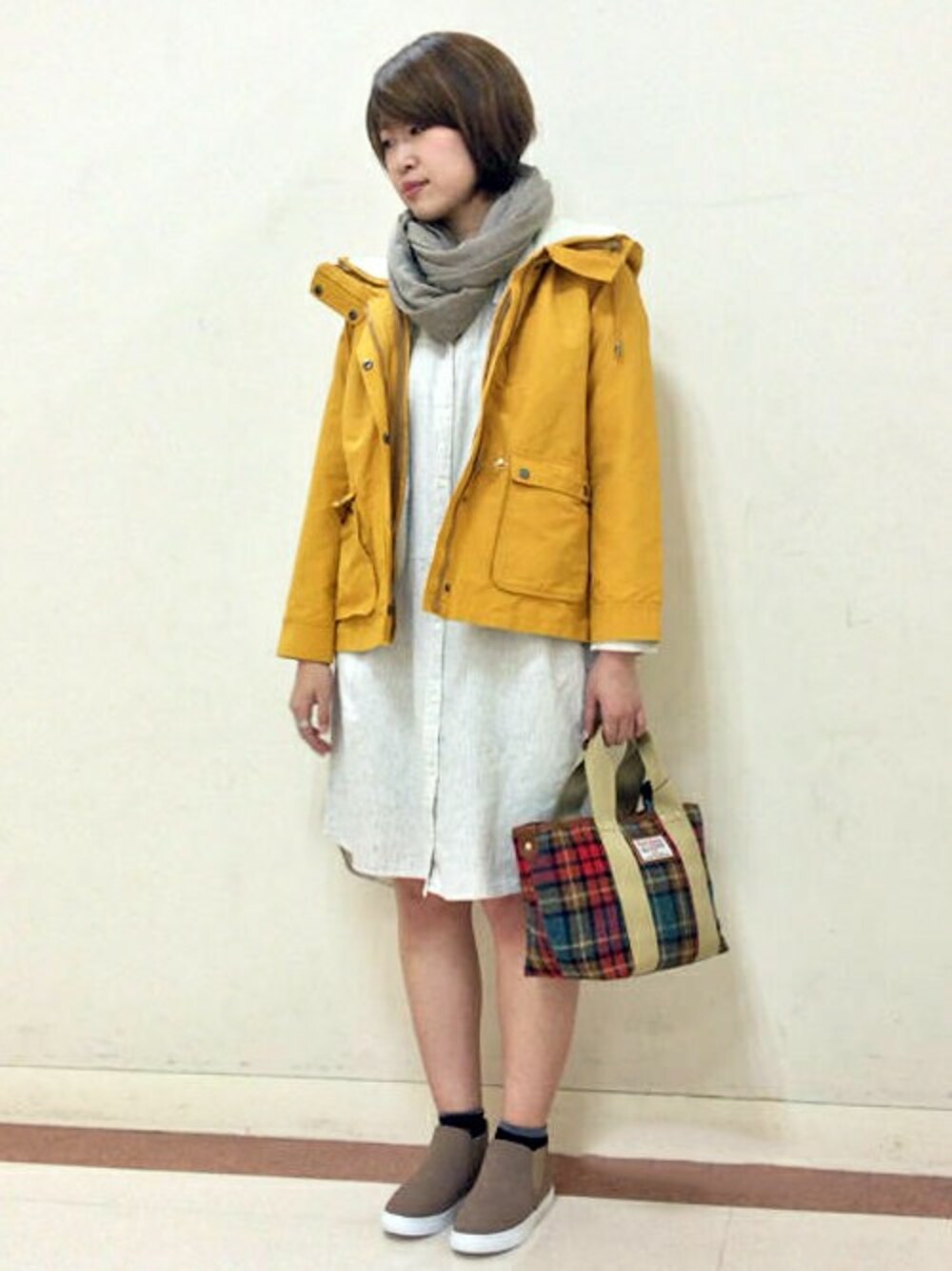 イエロー系のマウンテンパーカー、ホワイト系のその他アウター、ベージュ系のスニーカーを着用したレディースの秋コーディネートの1枚目の写真