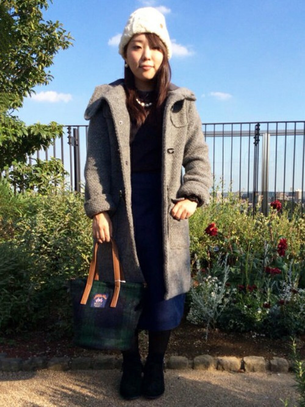 グレー系のダッフルコート、グリーン系のトートバッグ、ブルー系のスカートを着用したレディースの秋コーディネートの1枚目の写真