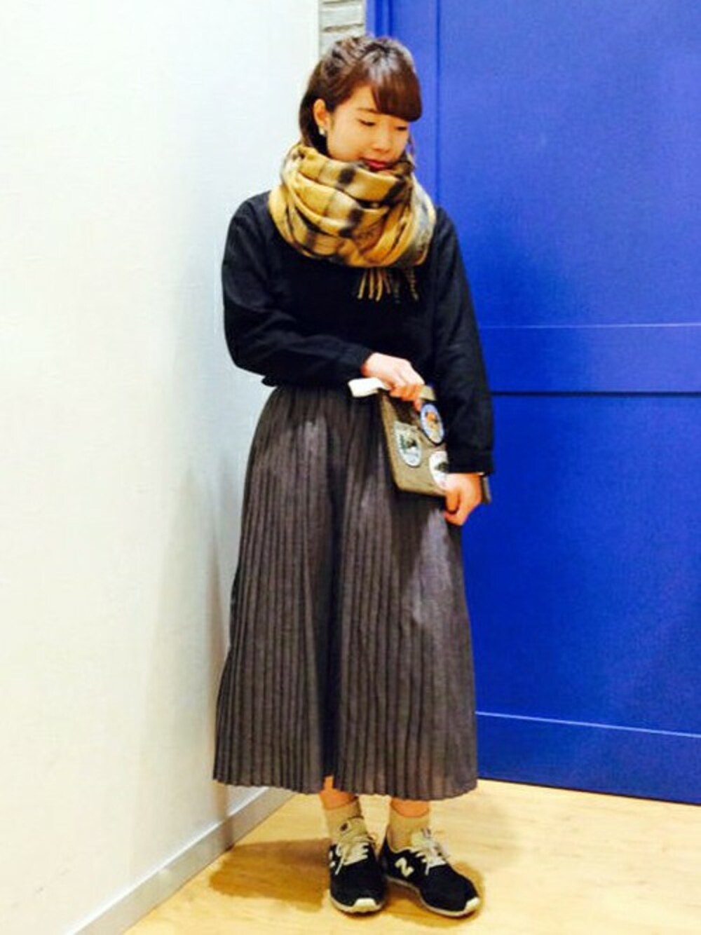 ブラウン系のクラッチバッグ、ブラック系のTシャツ/カットソー、グレー系のスカートを着用したレディースの秋コーディネートの1枚目の写真