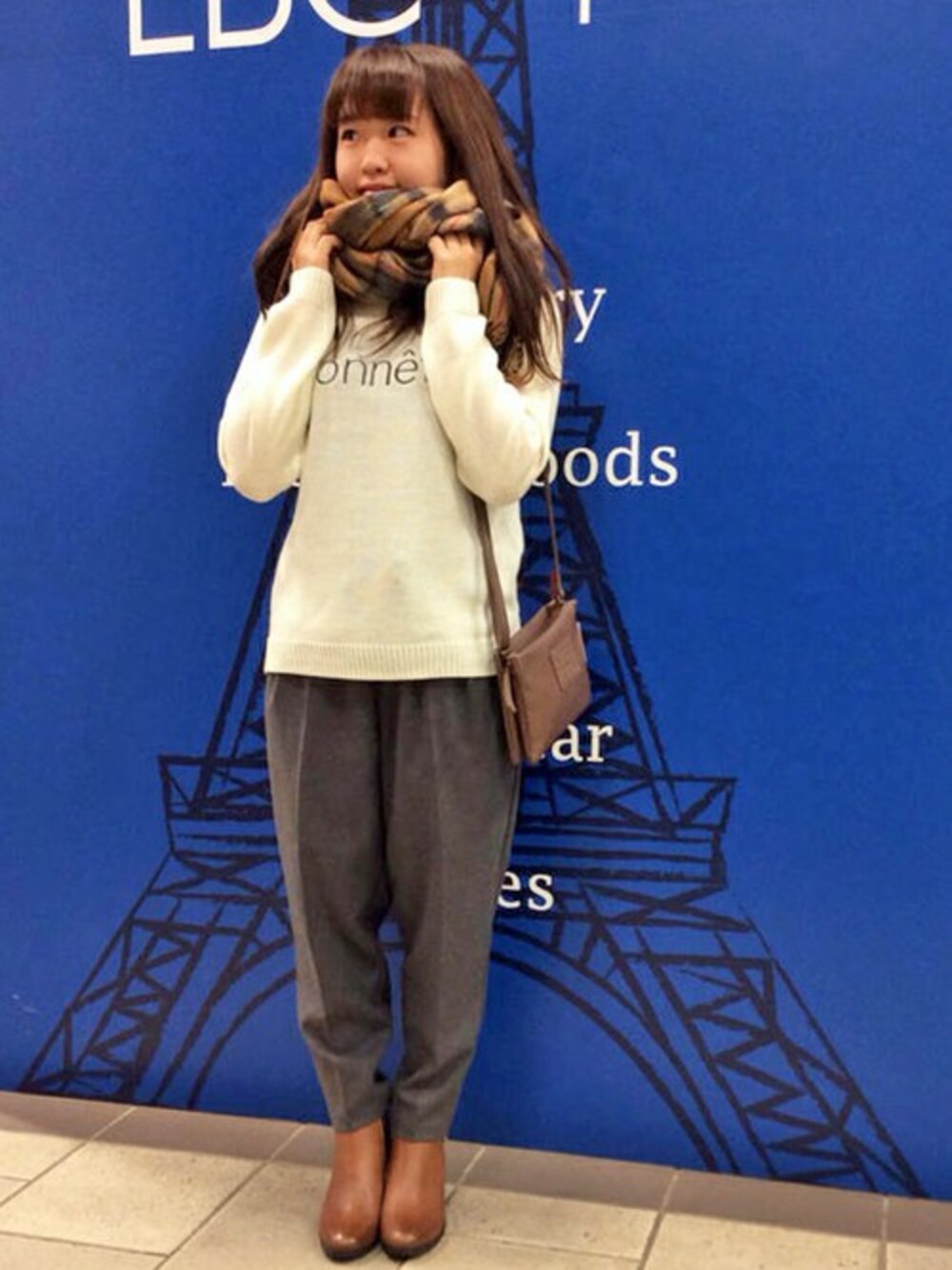 グレー系のその他パンツ、ホワイト系のニット/セーター、ブラウン系のショルダーバッグを着用したレディースの冬コーディネートの1枚目の写真