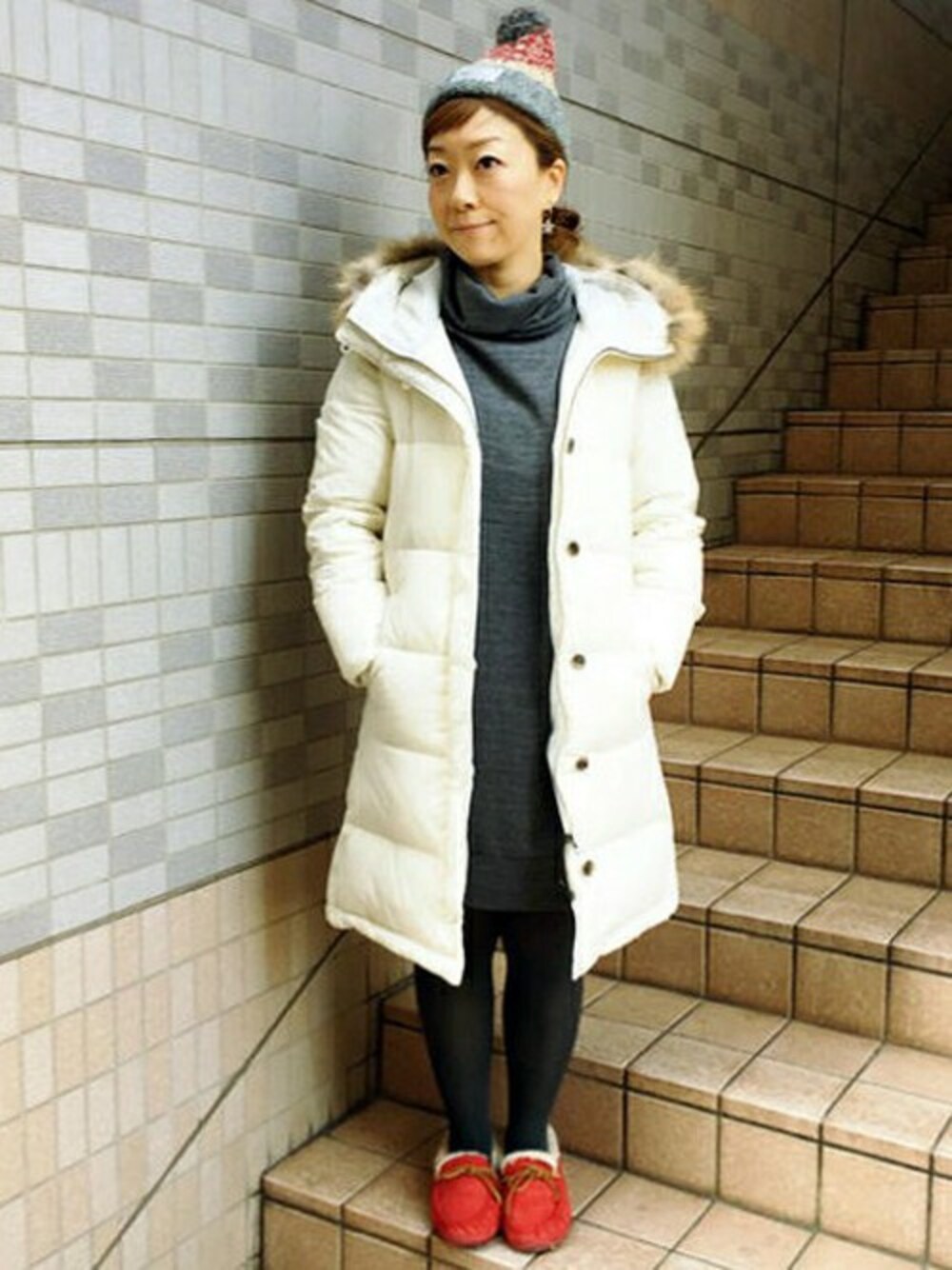 ホワイト系のダウンジャケット/コート、グレー系のワンピース、ブラウン系のニットキャップ/ビーニーを着用したレディースの冬コーディネートの1枚目の写真