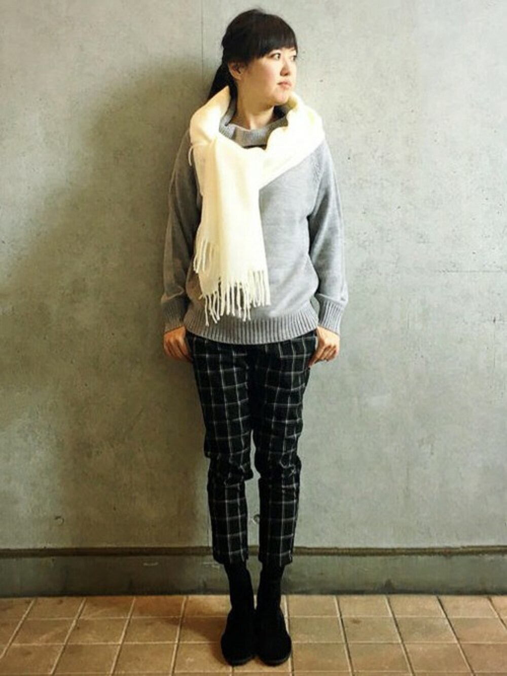 グレー系のニット/セーター、グレー系のその他パンツ、ホワイト系のマフラーを着用したレディースの冬コーディネートの1枚目の写真