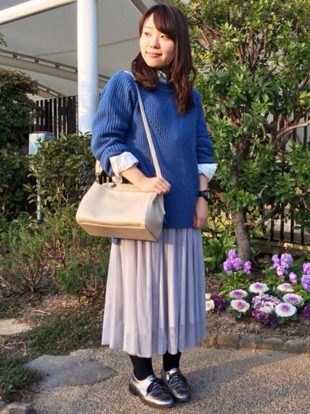グレー系のスカート、ホワイト系のショルダーバッグ、ブルー系のニット/セーターを着用したレディースの冬コーディネートの1枚目の写真