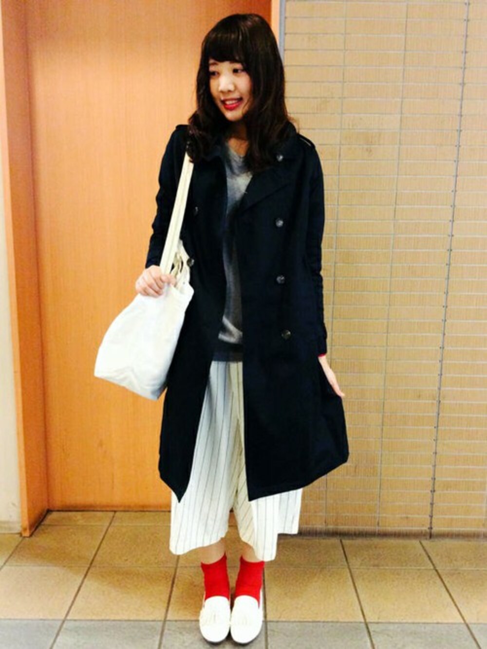 ブルー系のトレンチコート、グレー系のニット/セーター、ホワイト系のローファーを着用したレディースの冬コーディネートの1枚目の写真