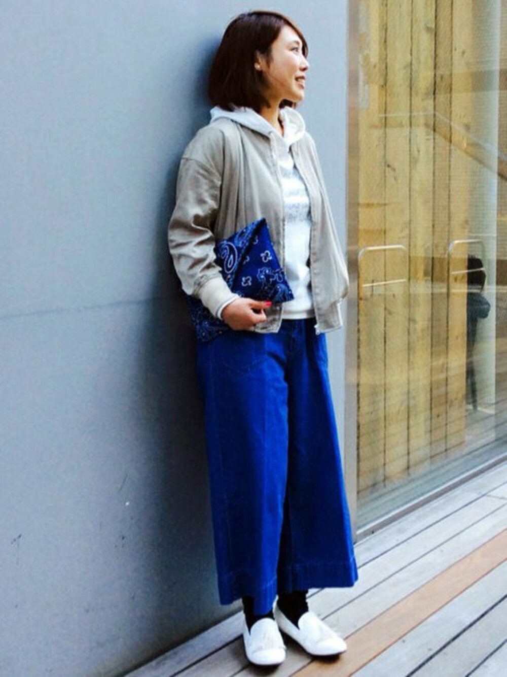 ホワイト系のパーカー、ブルー系のデニムパンツ、ブルー系のクラッチバッグを着用したレディースの冬コーディネートの1枚目の写真