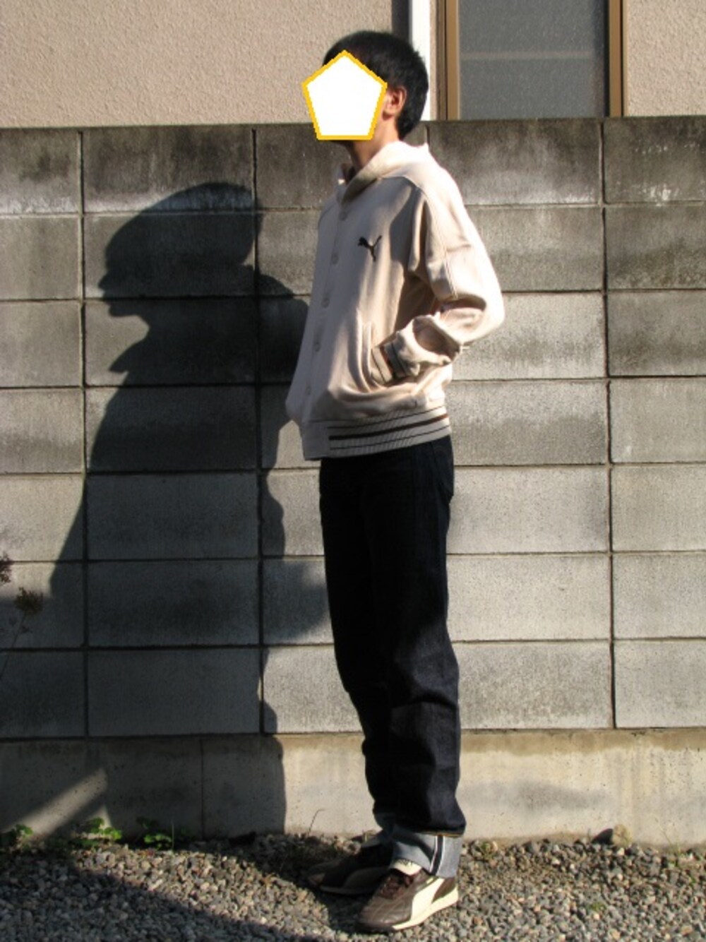 ベージュ系のパーカー、ブルー系のデニムパンツ、ブラウン系のスニーカーを着用したメンズの秋コーディネートの1枚目の写真