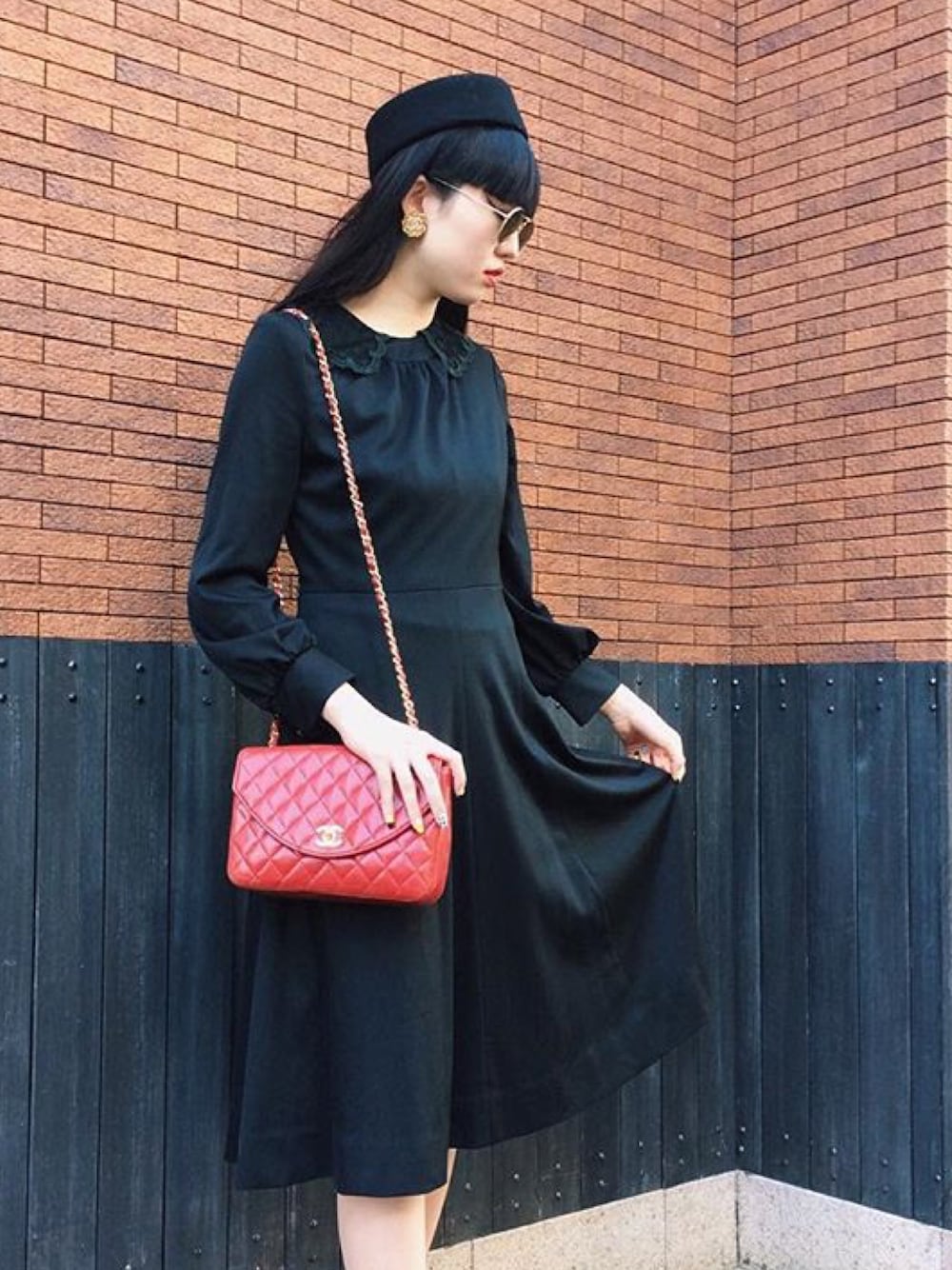 ブラック系のワンピース、レッド系のショルダーバッグを着用したレディースの秋コーディネートの1枚目の写真