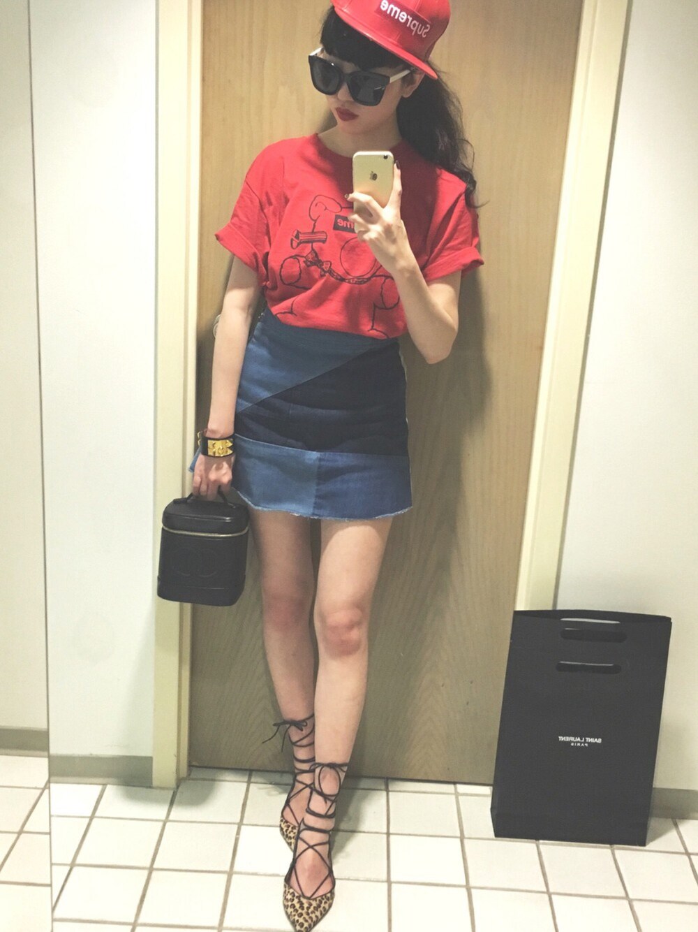 レッド系のTシャツ/カットソー、ブルー系のデニムスカート、ブラック系のハンドバッグを着用したレディースの冬コーディネートの1枚目の写真