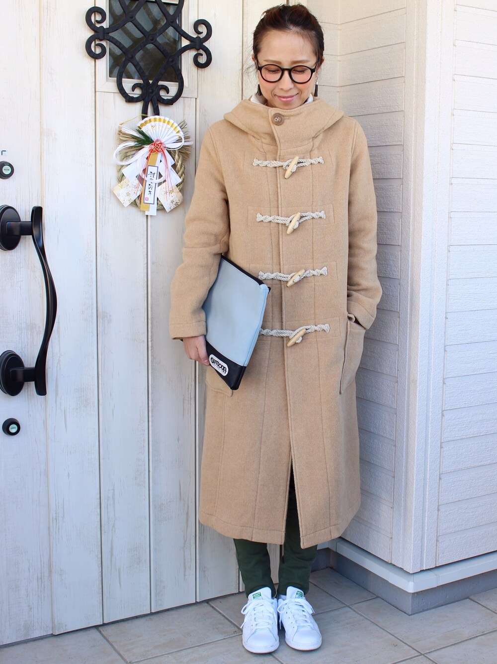 グレー系のクラッチバッグ、ベージュ系のTシャツ/カットソー、ホワイト系のスニーカーを着用したレディースの冬コーディネートの1枚目の写真