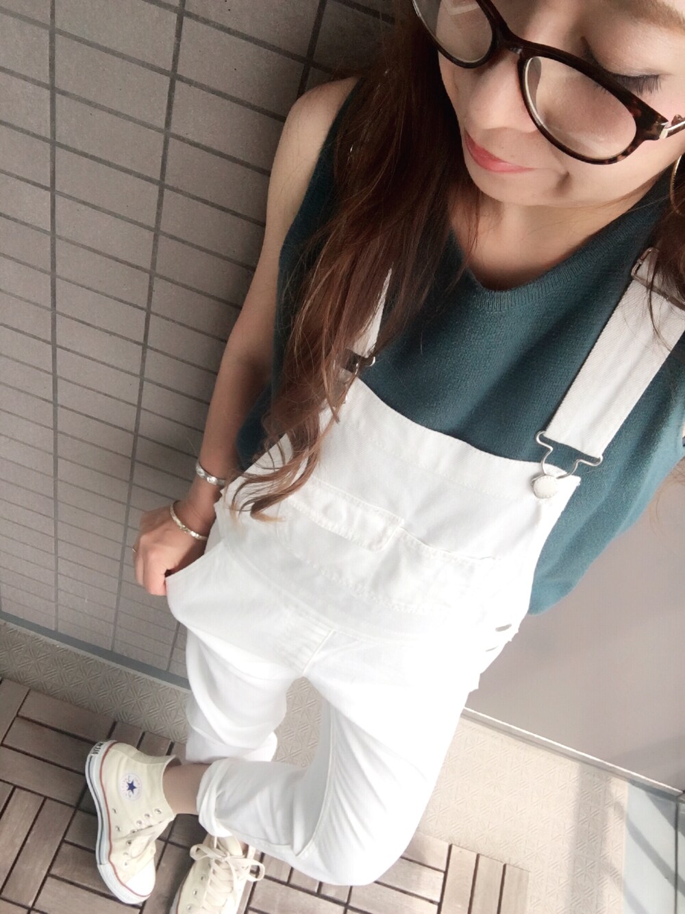 ホワイト系のサロペット/オーバーオール、グリーン系のニット/セーター、ベージュ系のスニーカーを着用したレディースの春コーディネートの1枚目の写真
