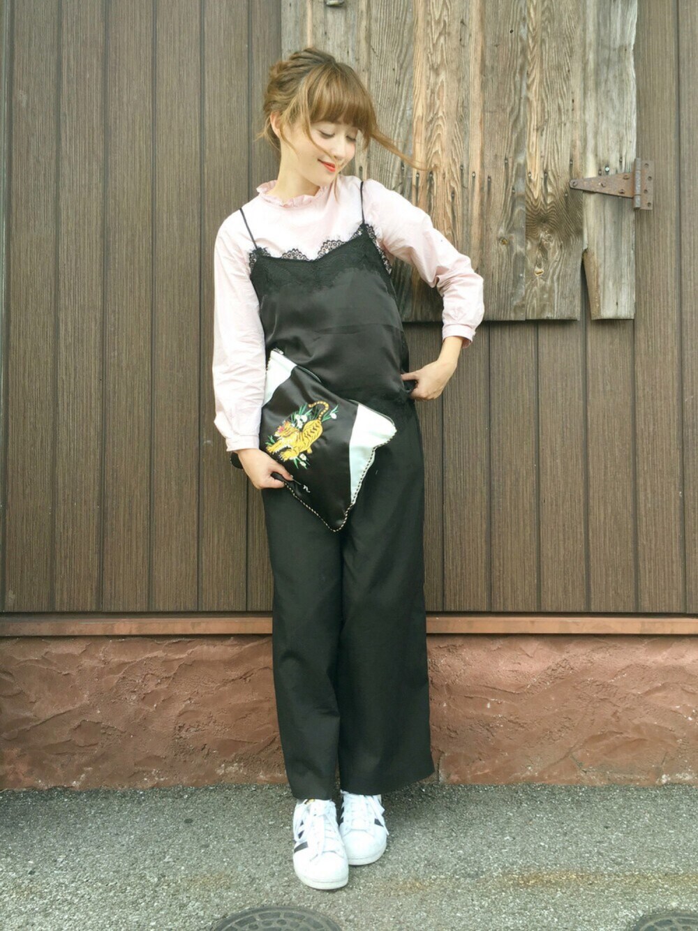 ブラック系のクラッチバッグ、ピンク系のシャツ/ブラウス、ホワイト系のスニーカーを着用したレディースの秋コーディネートの1枚目の写真