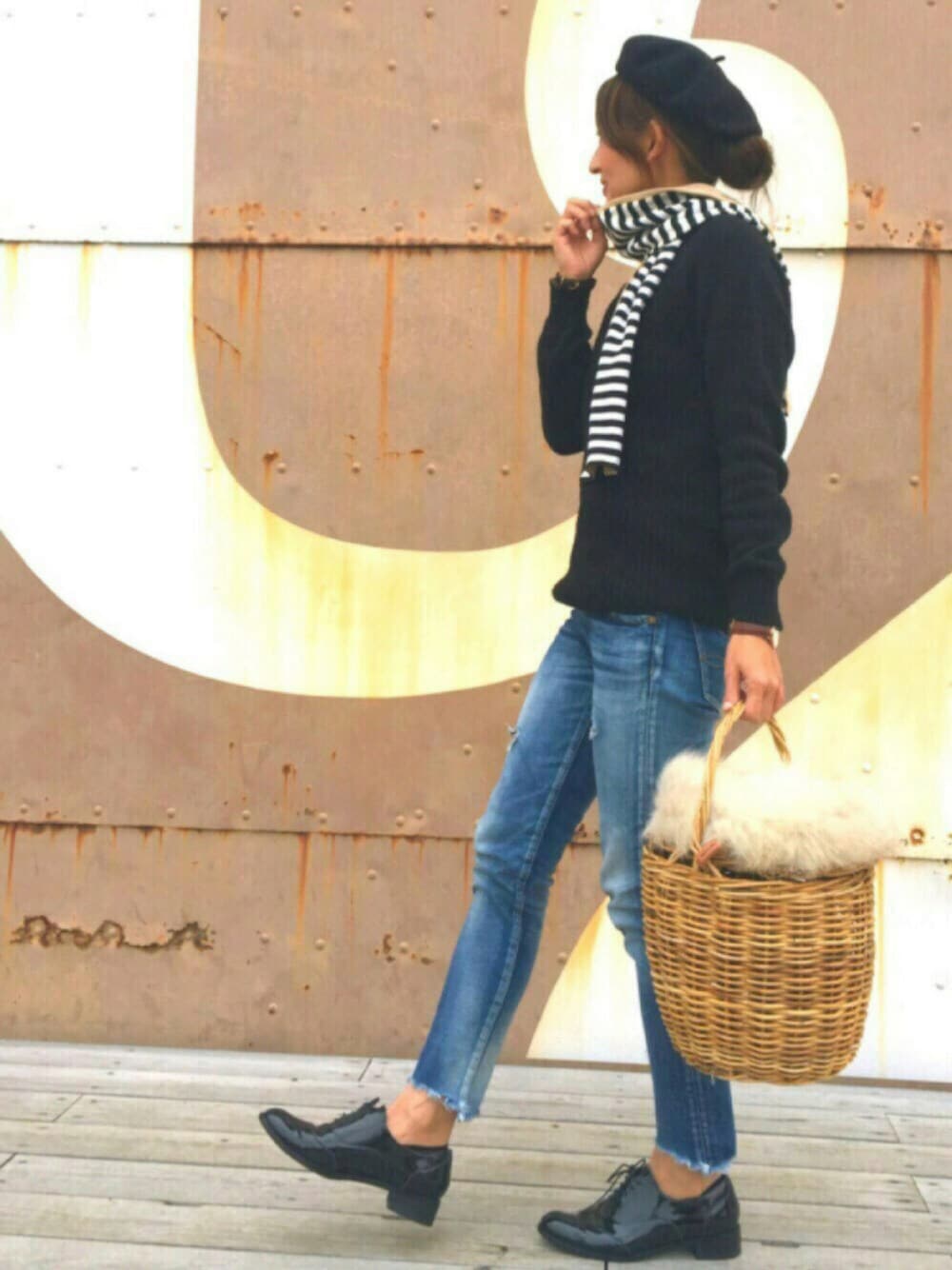 ブルー系のデニムパンツ、ブラウン系のかごバッグ、ブラック系のドレスシューズを着用したレディースの秋コーディネートの1枚目の写真