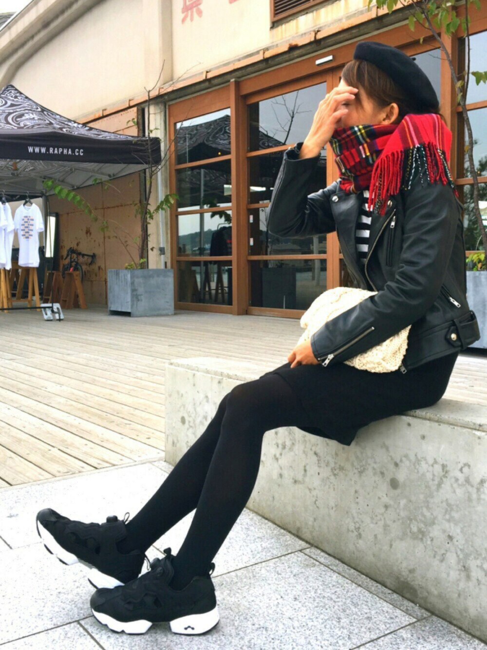 ブラック系のライダースジャケット、ブラック系のスカート、ホワイト系のショルダーバッグを着用したレディースの冬コーディネートの1枚目の写真