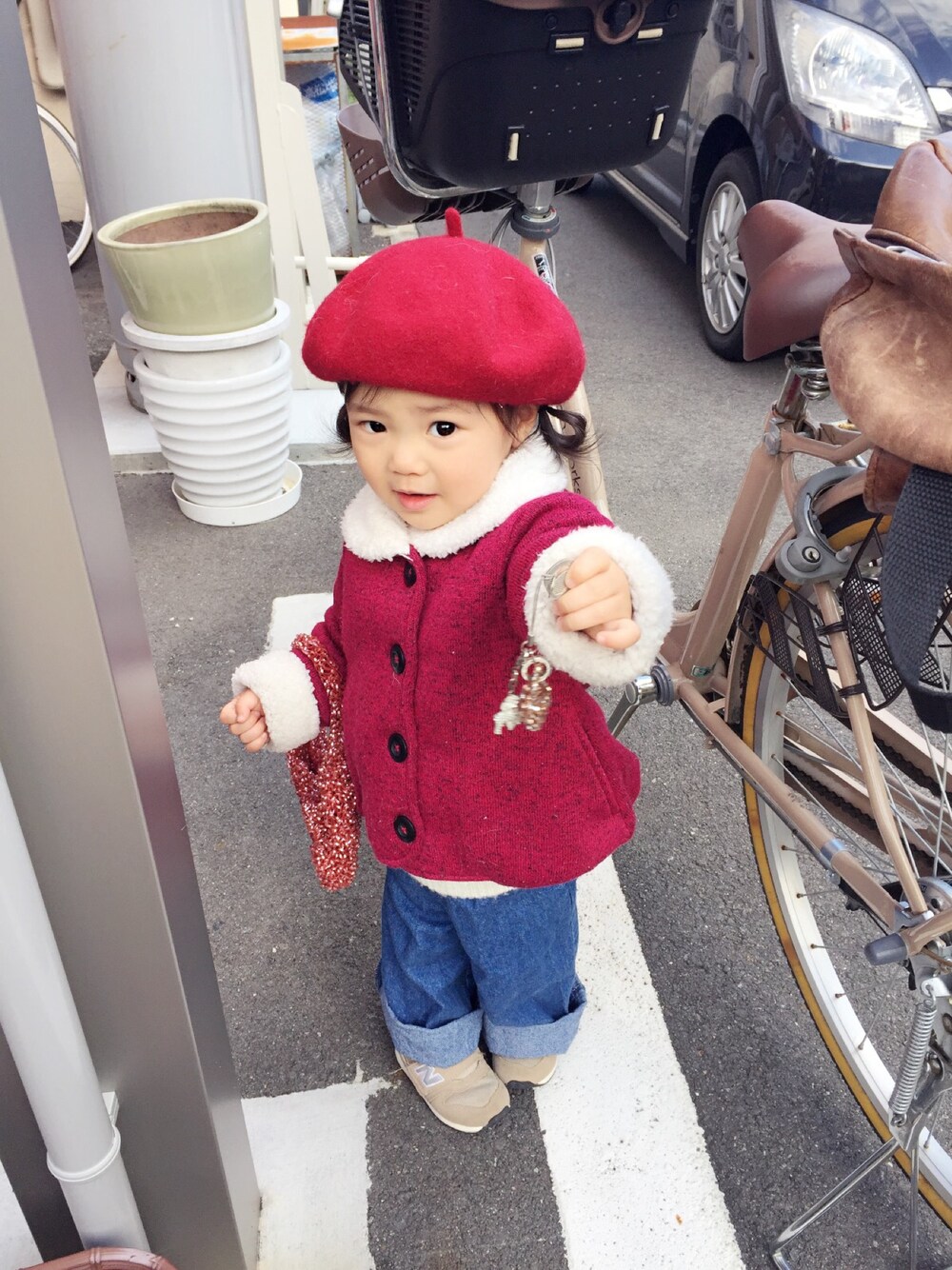 レッド系のダウンジャケット/コート、ブルー系のデニムパンツ、ベージュ系のスニーカーを着用したキッズの冬コーディネートの1枚目の写真