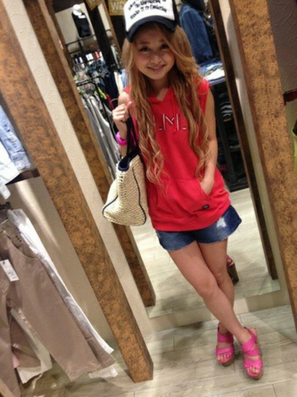 レッド系のパーカー、ブルー系のデニムパンツ、ベージュ系のトートバッグを着用したレディースの春コーディネートの1枚目の写真