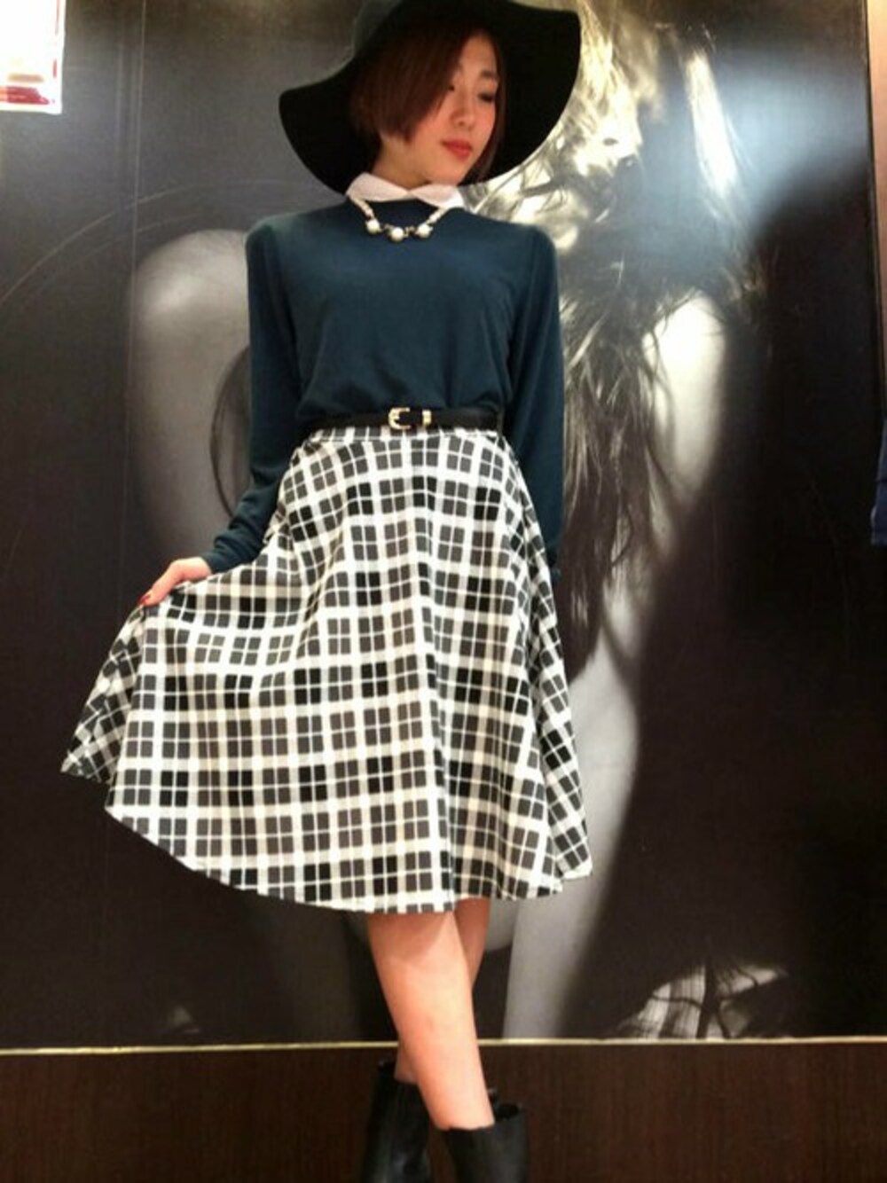 ブラック系のスカート、グリーン系のニット/セーター、ブラック系のブーツを着用したレディースの冬コーディネートの1枚目の写真