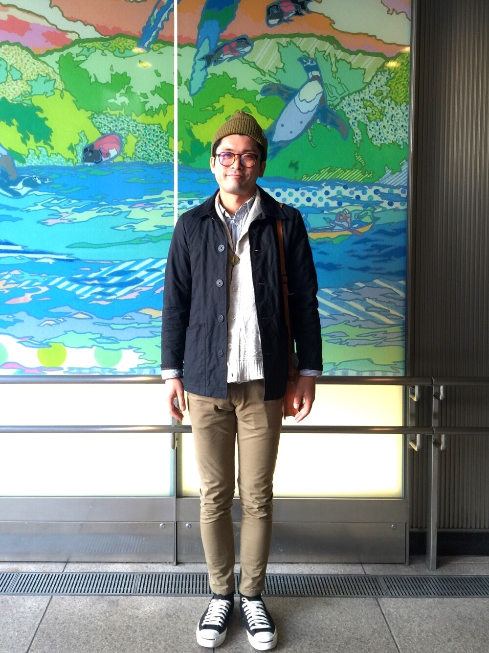 ブラック系のカバーオール、ベージュ系のカーディガン/ボレロ、ベージュ系のチノパンツを着用したメンズの秋コーディネートの1枚目の写真