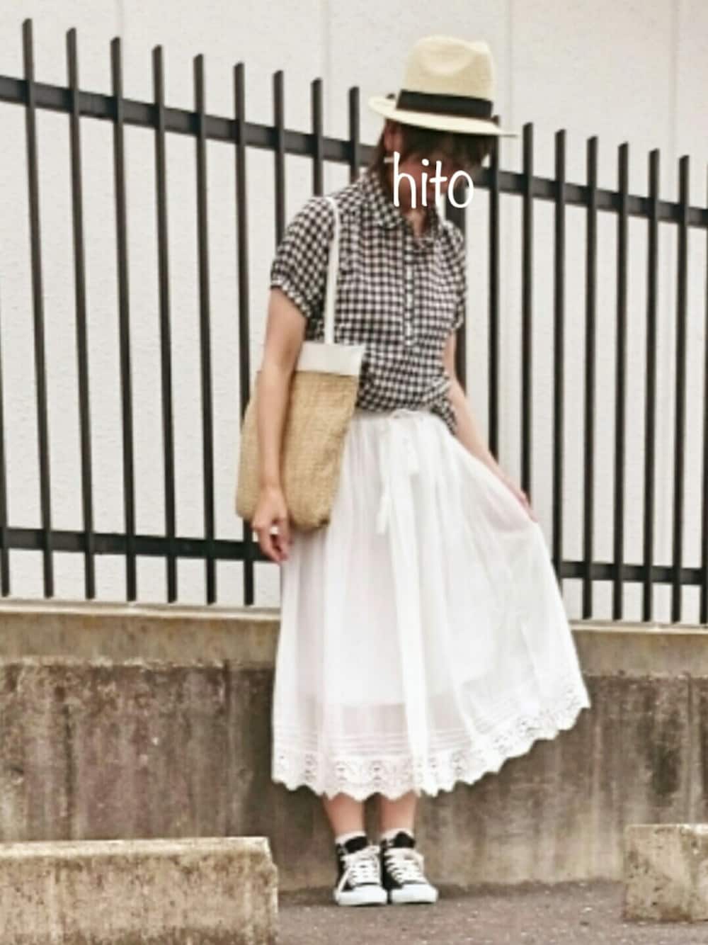 ホワイト系のスカート、ベージュ系のクラッチバッグ、ブラック系のスニーカーを着用したレディースの春コーディネートの1枚目の写真