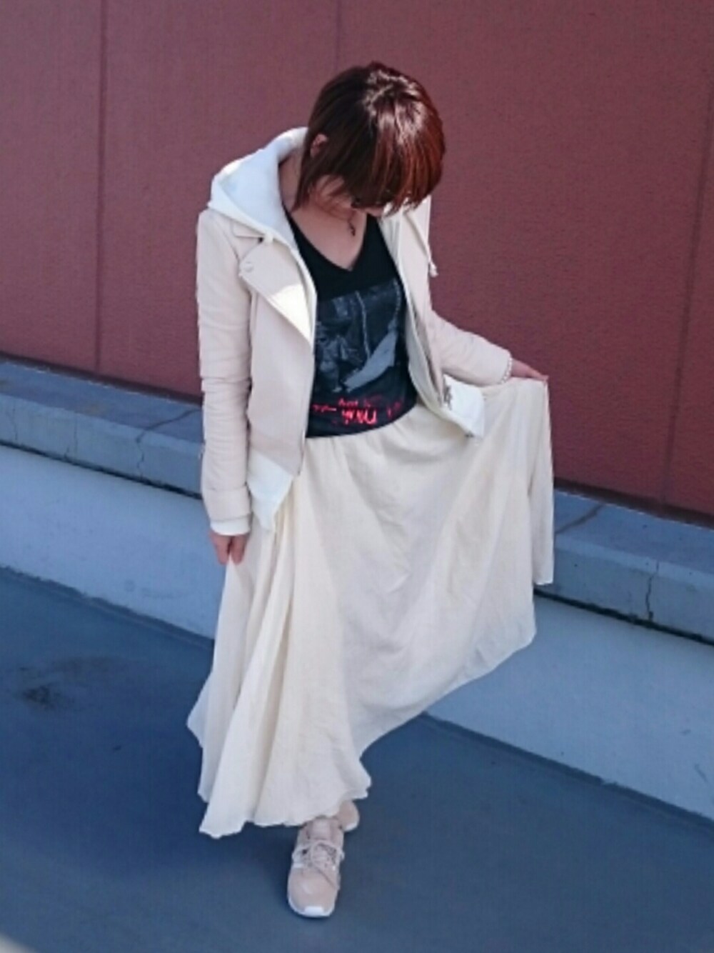 ホワイト系のスカート、ホワイト系のライダースジャケット、ベージュ系のスニーカーを着用したレディースの秋コーディネートの1枚目の写真
