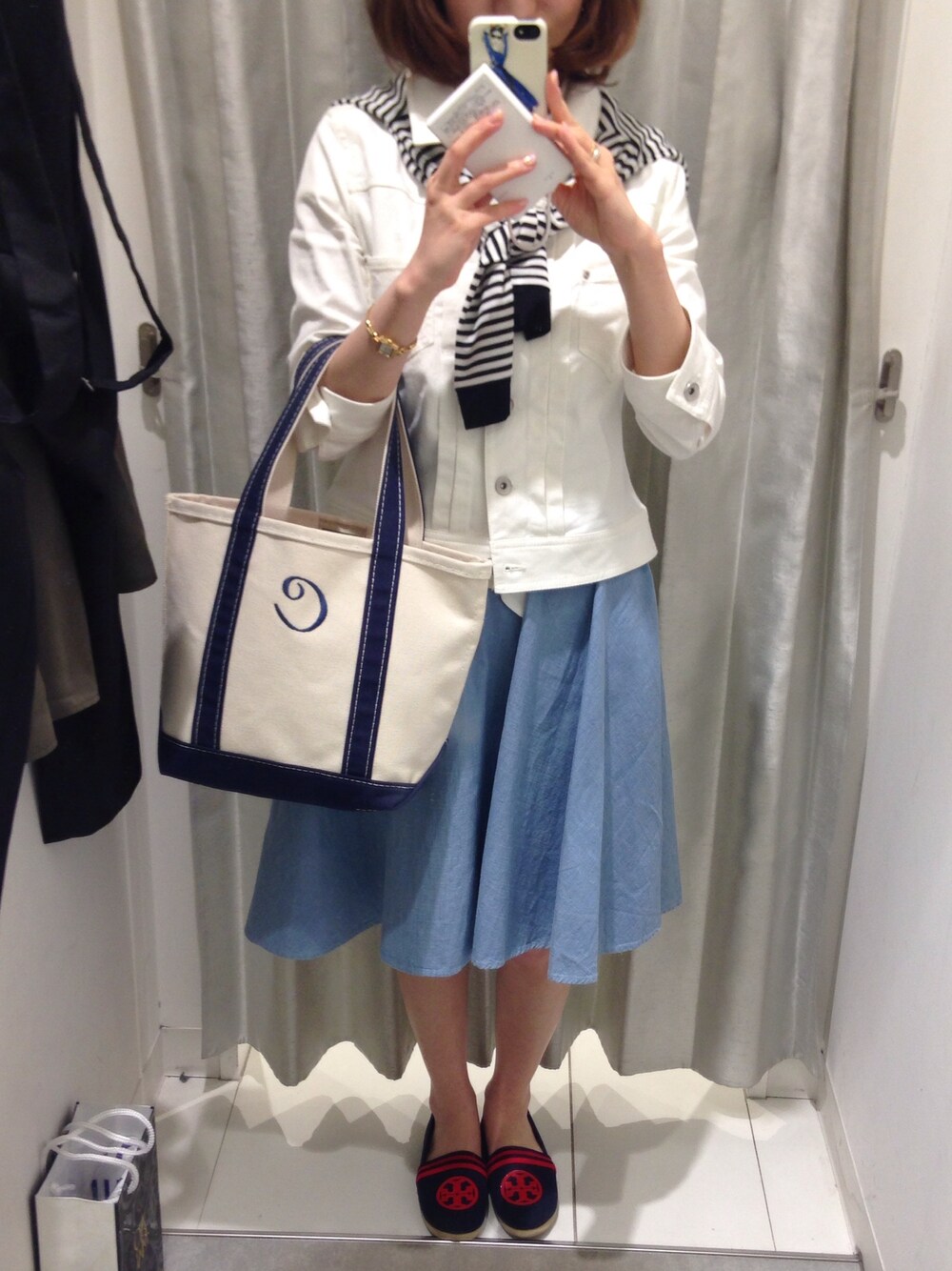 ブルー系のトートバッグ、ブルー系のデニムスカート、ブルー系のスニーカーを着用したレディースの春コーディネートの1枚目の写真