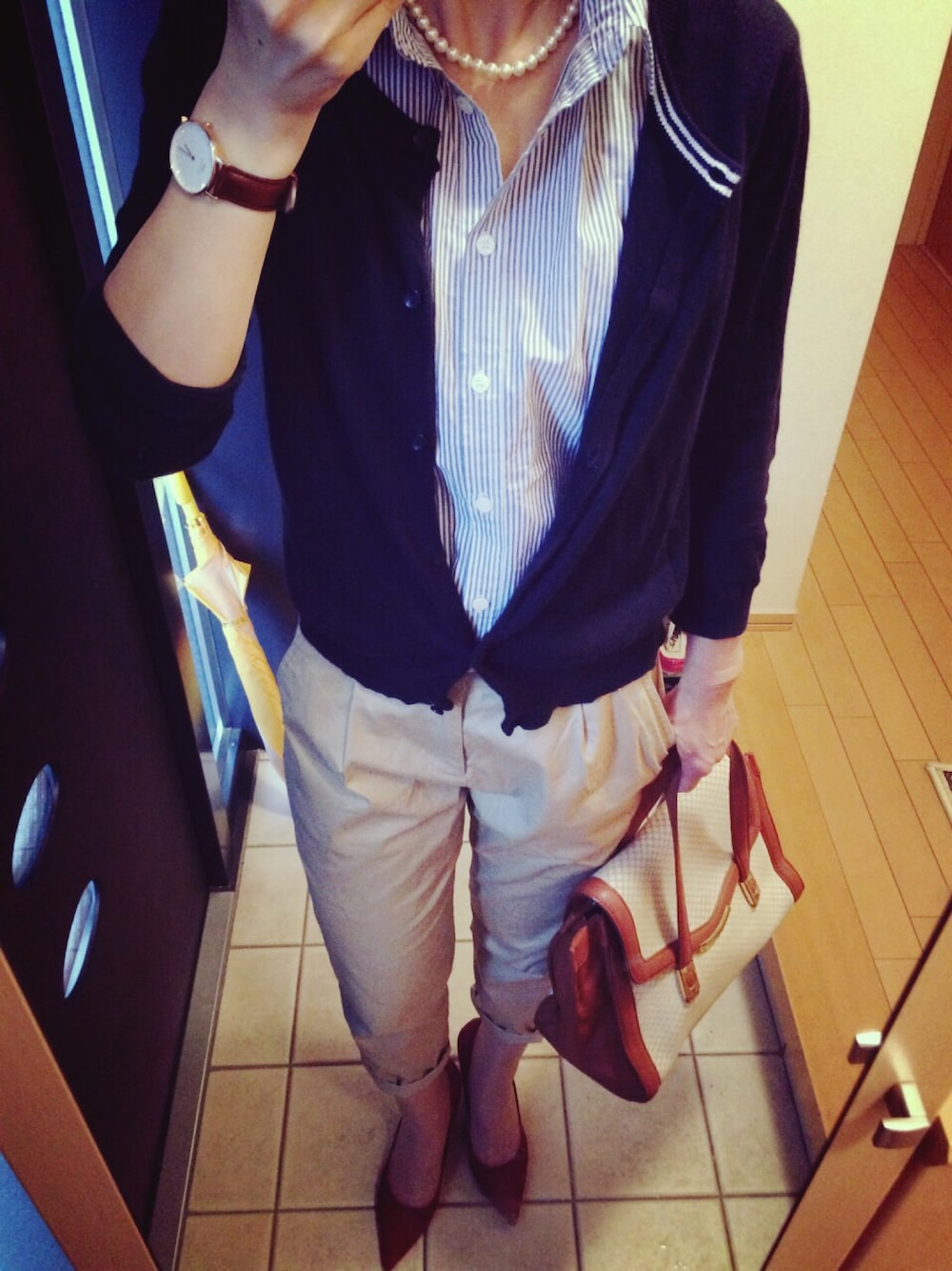 ブルー系のカーディガン/ボレロ、ブルー系のシャツ/ブラウス、ベージュ系のハンドバッグを着用したレディースの秋コーディネートの1枚目の写真