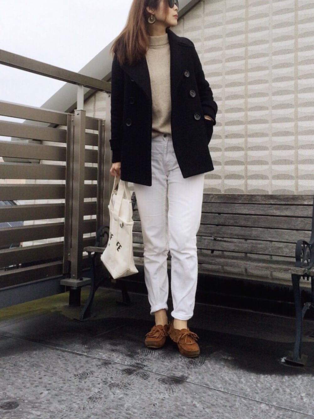 ブラック系のピーコート、ベージュ系のニット/セーター、ホワイト系のデニムパンツを着用したレディースの冬コーディネートの1枚目の写真
