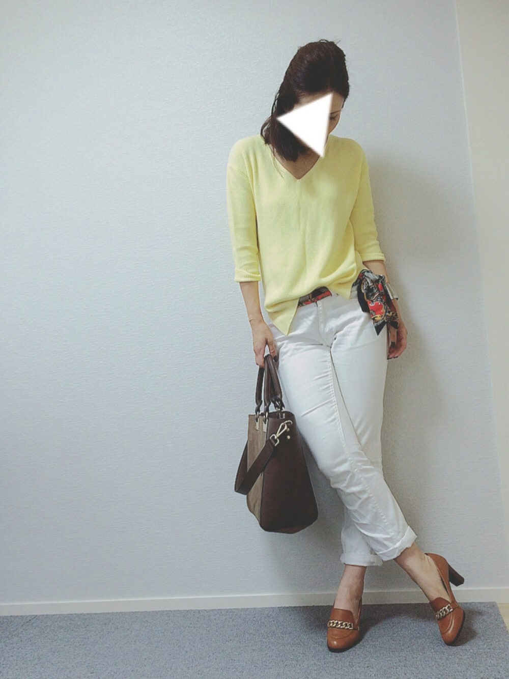 イエロー系のニット/セーター、ホワイト系のデニムパンツ、ブラウン系のパンプスを着用したレディースの夏コーディネートの1枚目の写真