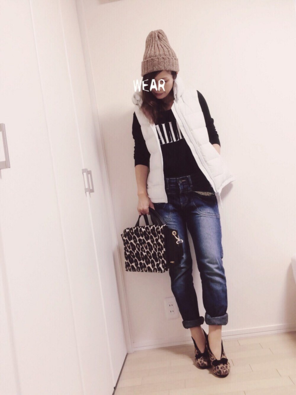 ホワイト系のダウンベスト、イエロー系のブーツ、ブラック系のニット/セーターを着用したレディースの秋コーディネートの1枚目の写真