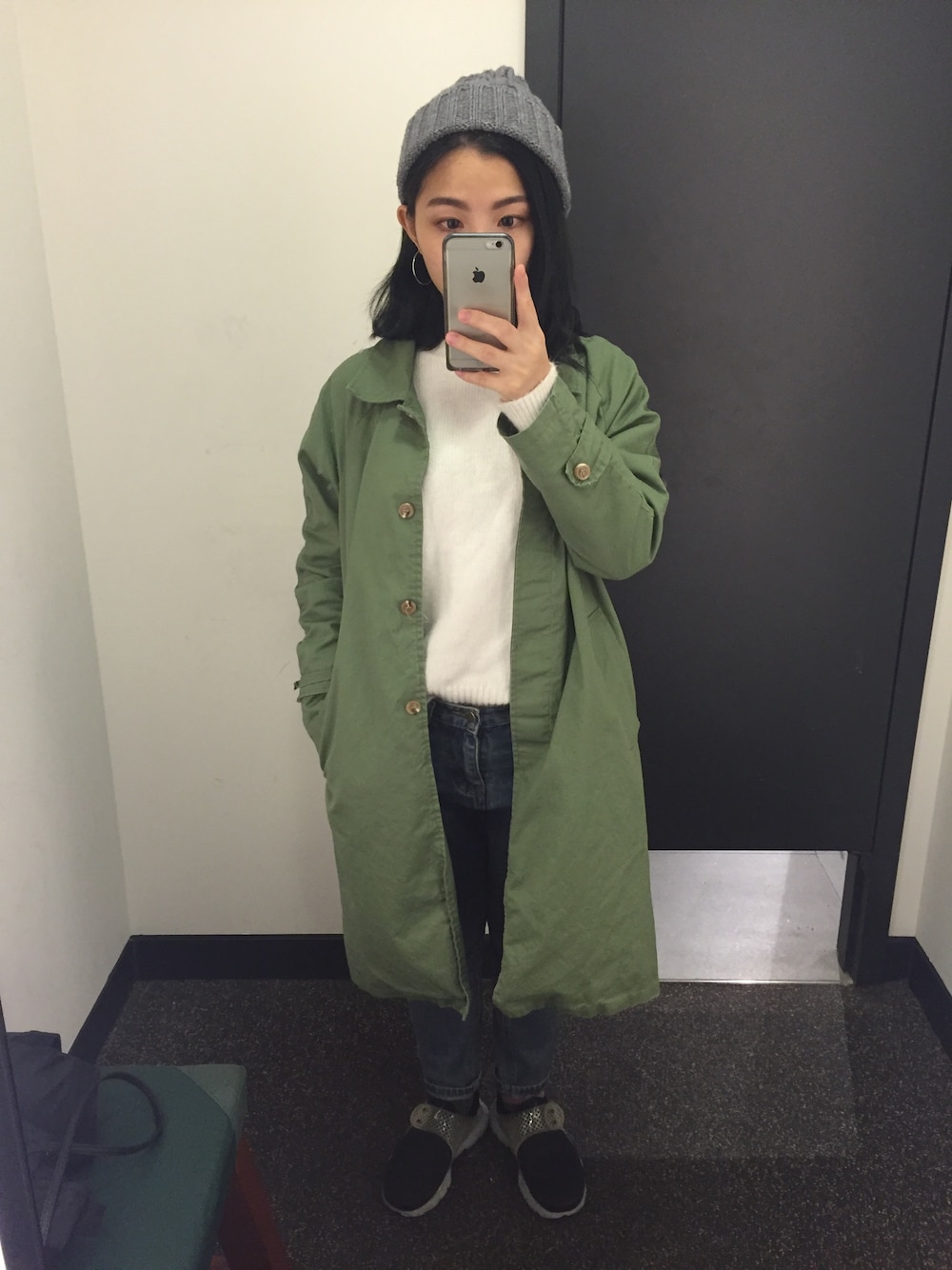 ホワイト系のトップス、ブラック系のスニーカー、グリーン系のトレンチコートを着用したレディースの秋コーディネートの1枚目の写真