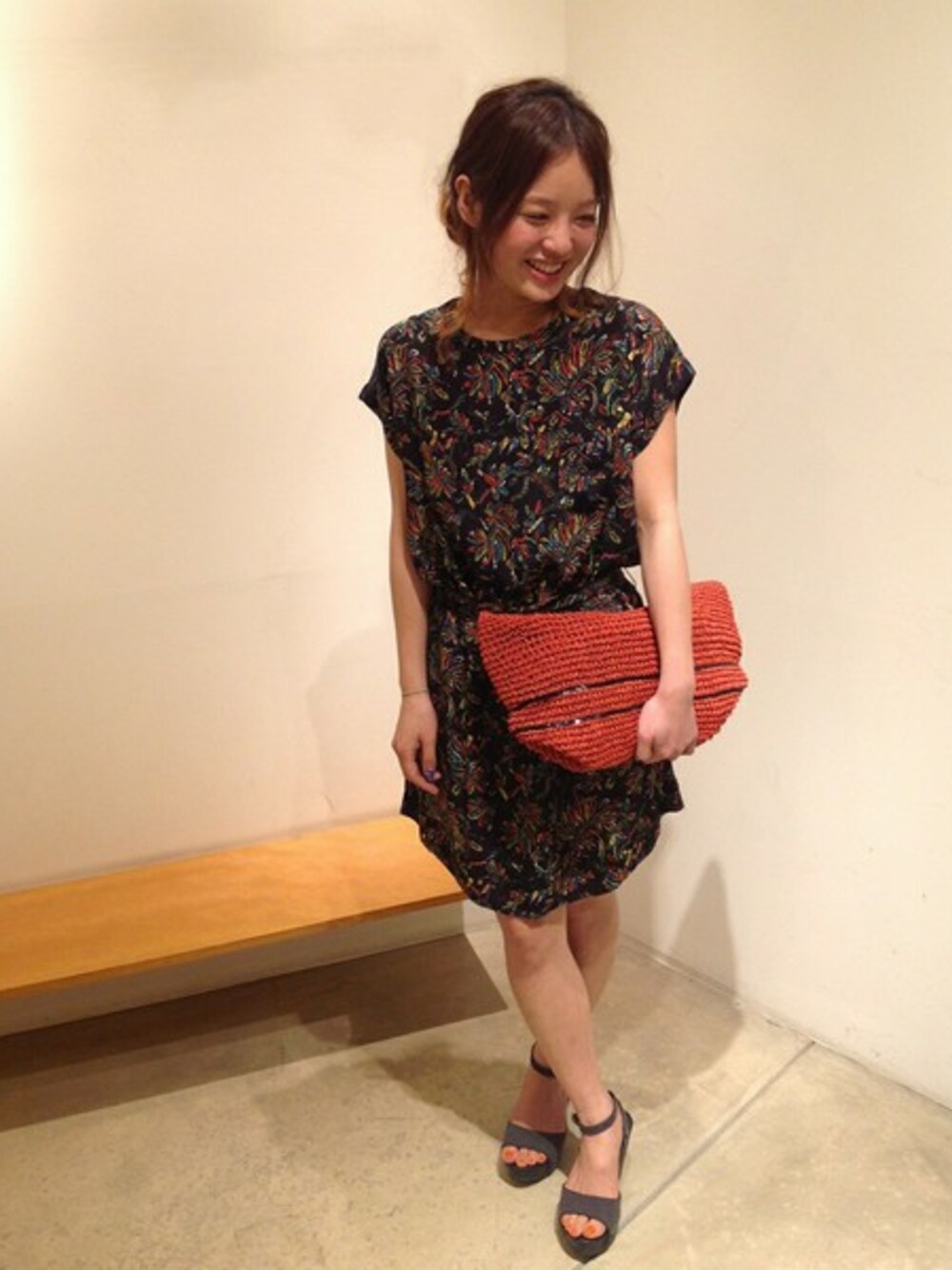 ブラック系のサンダル、オレンジ系のかごバッグ、ブラック系のワンピースを着用したレディースの春コーディネートの1枚目の写真