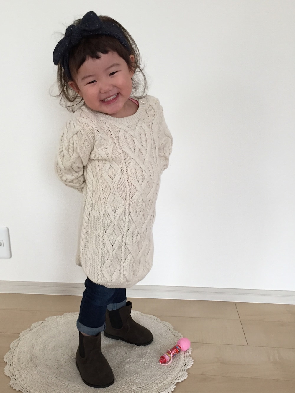 ホワイト系のワンピース、ブルー系のデニムパンツ、グリーン系のブーツを着用したキッズの秋コーディネートの1枚目の写真