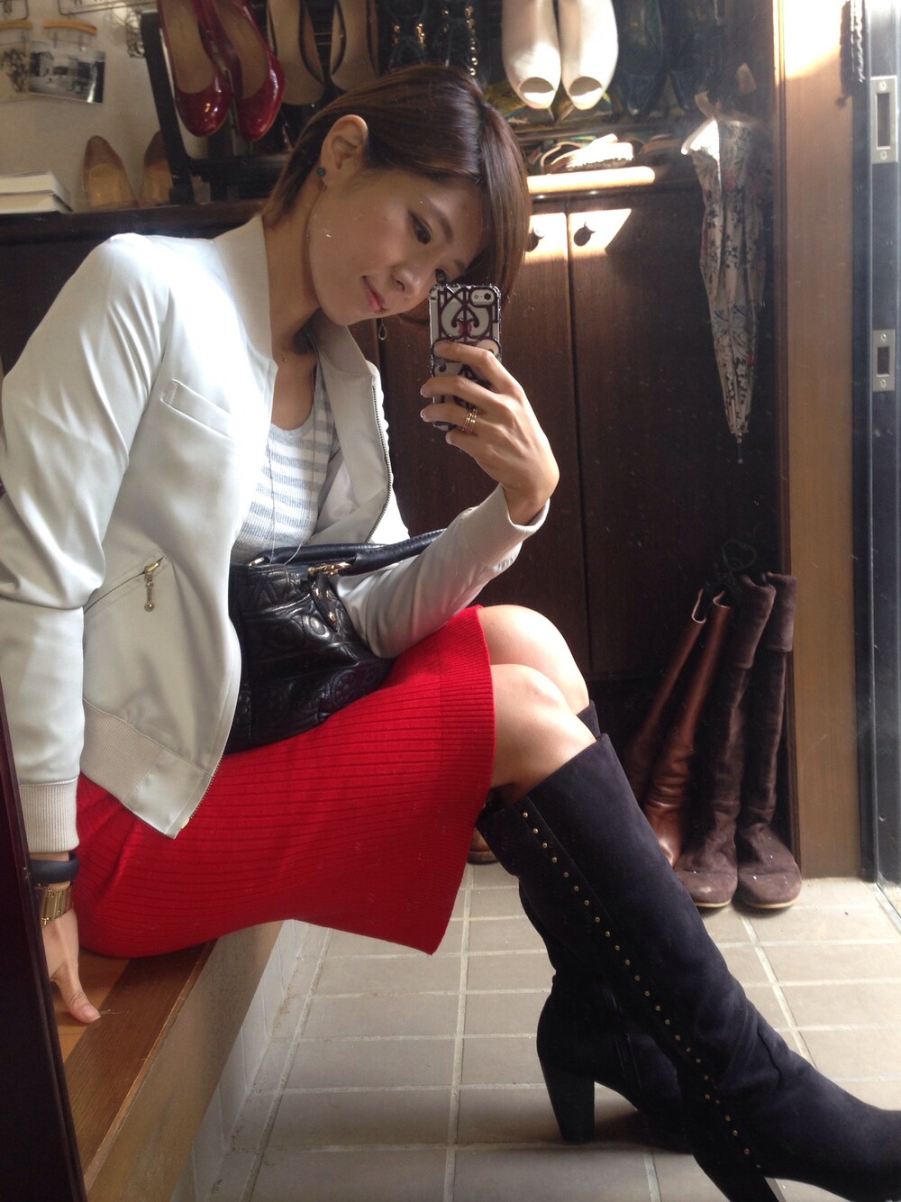 ホワイト系のブルゾン、レッド系のスカート、ブラック系のハンドバッグを着用したレディースの秋コーディネートの1枚目の写真