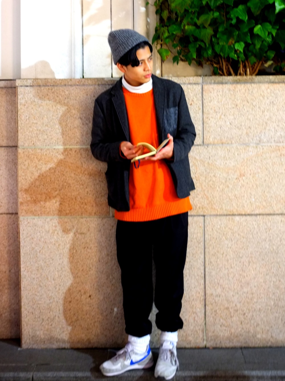 グレー系のテーラードジャケット、オレンジ系のニット/セーター、ホワイト系のTシャツ/カットソーを着用したメンズの冬コーディネートの1枚目の写真