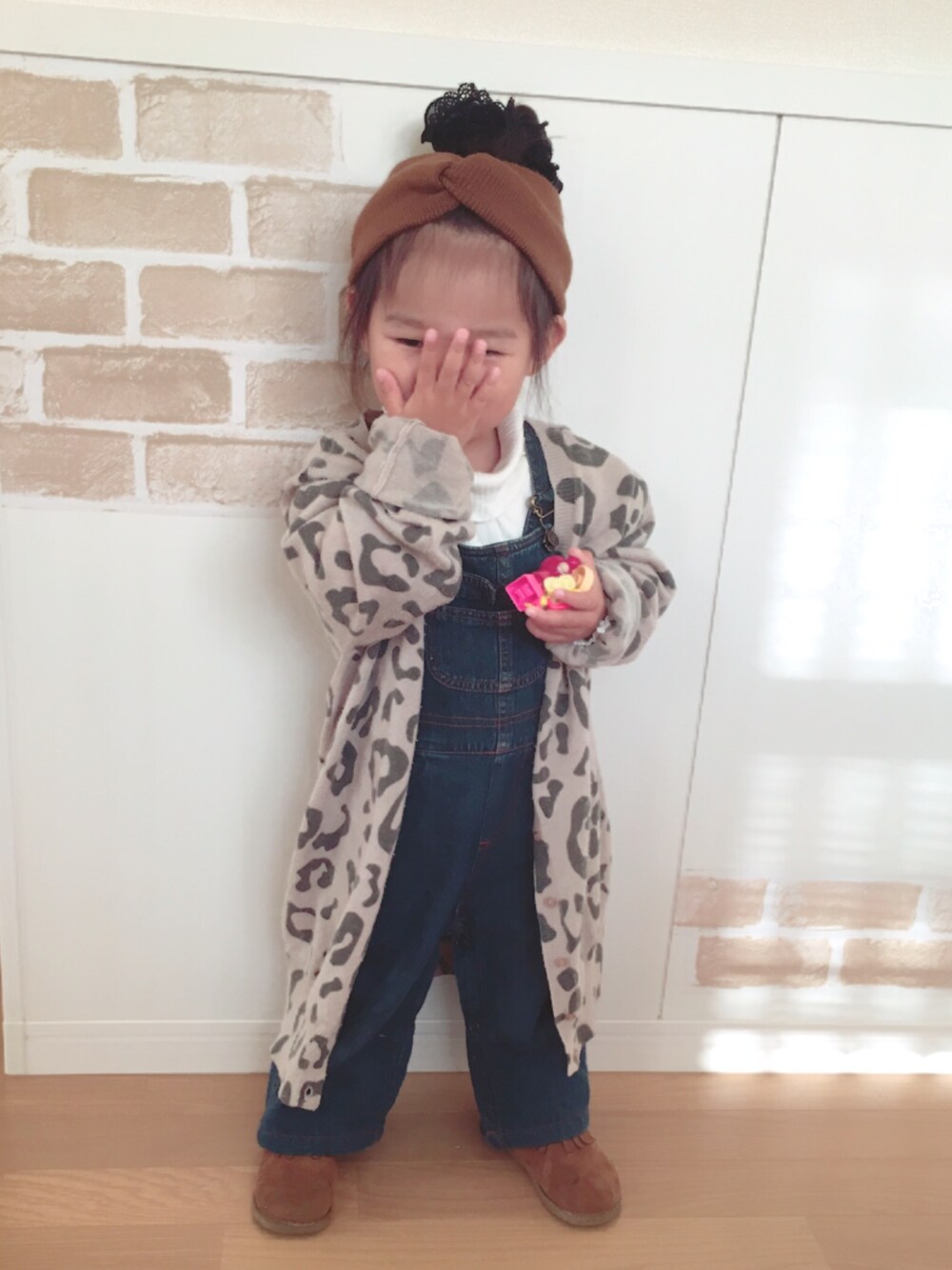 ブラウン系のカーディガン/ボレロ、ホワイト系のニット/セーター、ブラウン系のブーツを着用したキッズの秋コーディネートの1枚目の写真