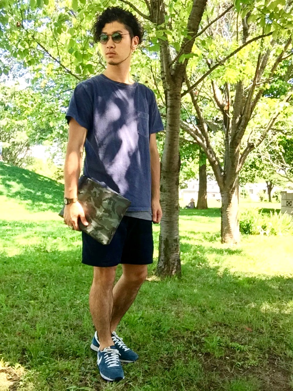 ブルー系のTシャツ/カットソー、グリーン系のクラッチバッグ、ブルー系のパンツを着用したメンズの夏コーディネートの1枚目の写真