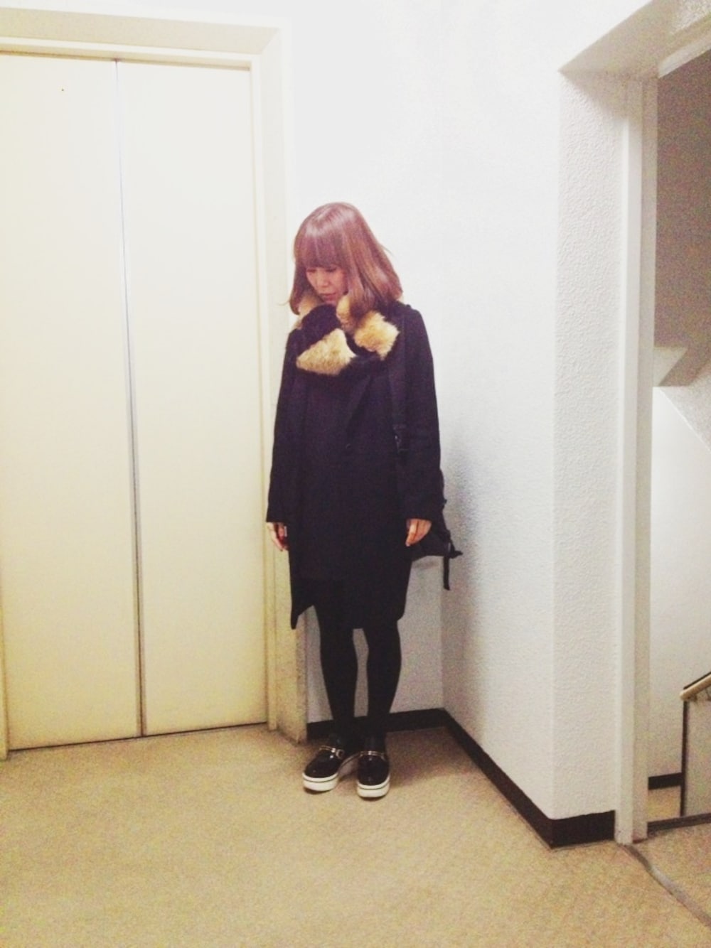 ブラック系のチェスターコート、ブラック系のワンピースを着用したレディースの冬コーディネートの1枚目の写真