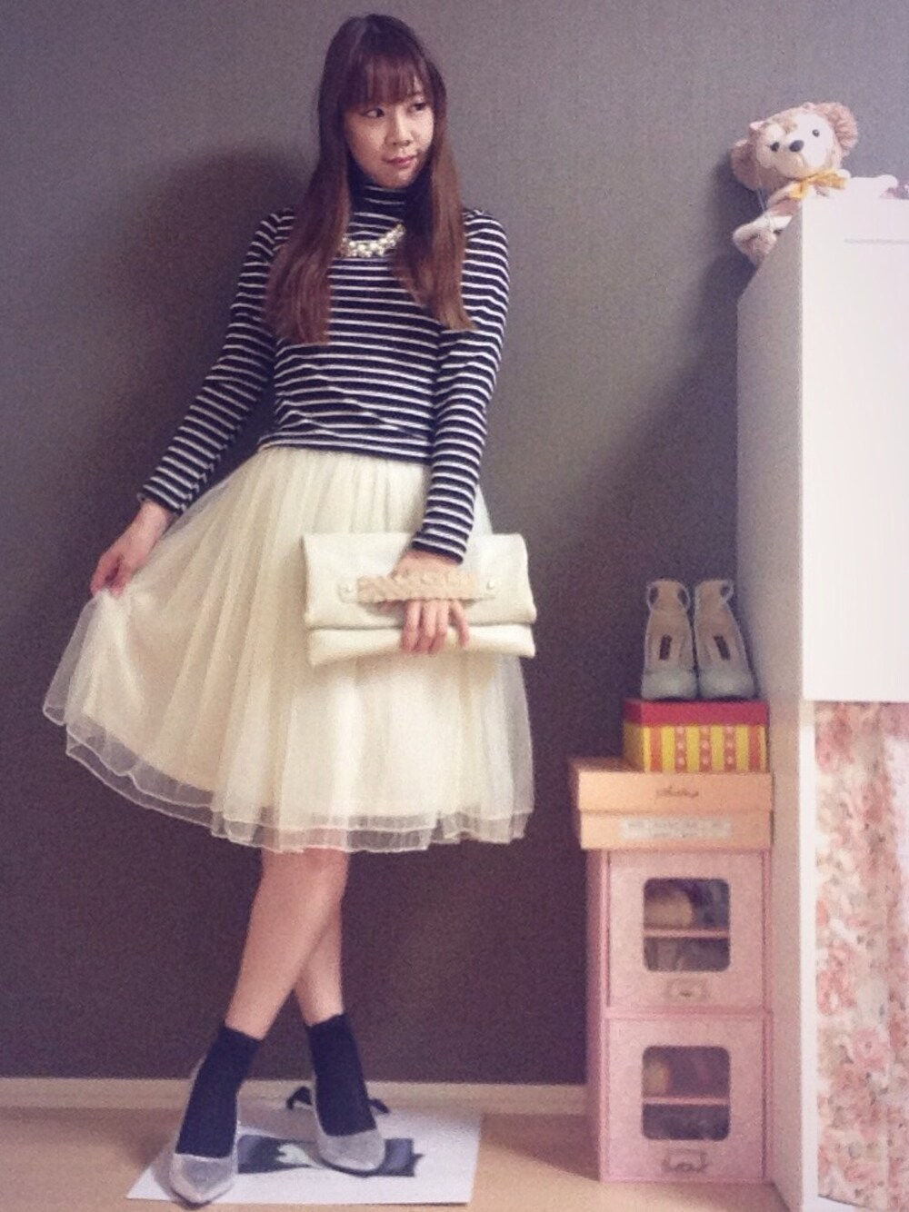 ベージュ系のトレンチコート、ブラック系のニット/セーター、ホワイト系のスカートを着用したレディースの春コーディネートの1枚目の写真