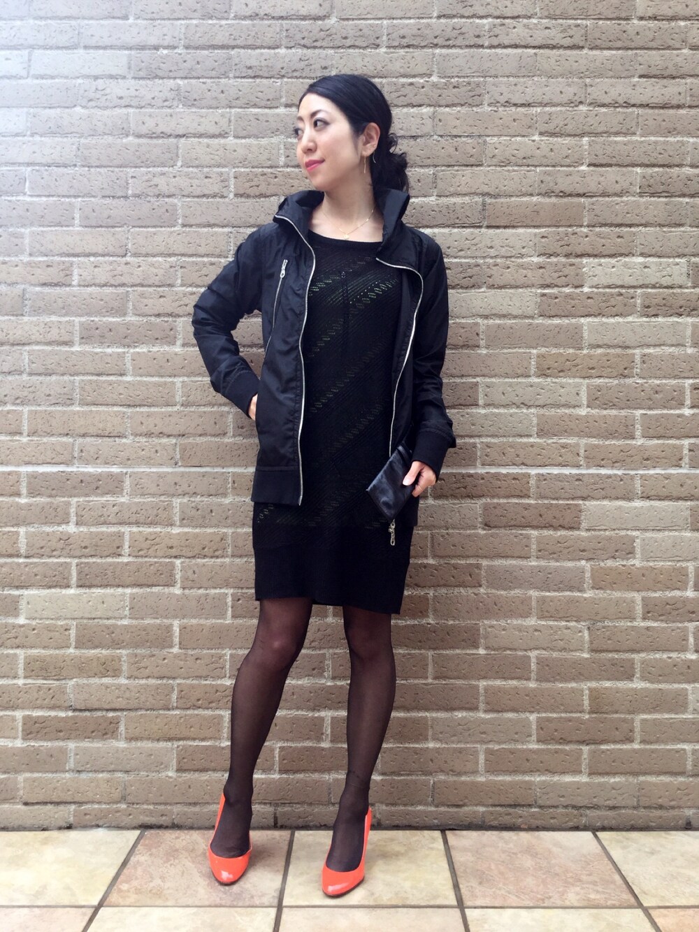 ブラック系のワンピース/ドレス、オレンジ系のパンプス、ブラック系のクラッチバッグを着用したレディースの春コーディネートの1枚目の写真
