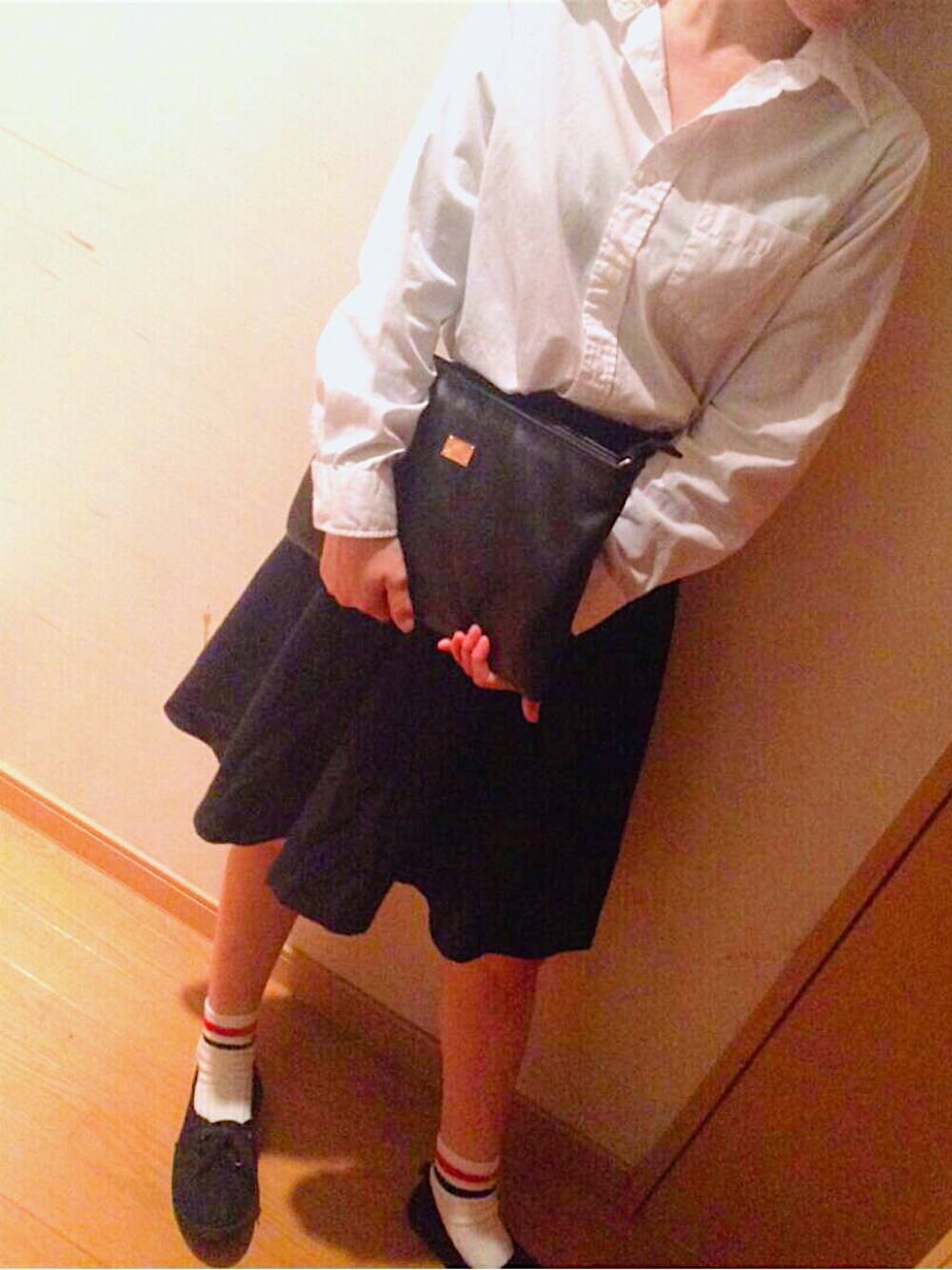 ホワイト系のトップス、ブラック系のクラッチバッグ、その他のスカートを着用したレディースの秋コーディネートの1枚目の写真