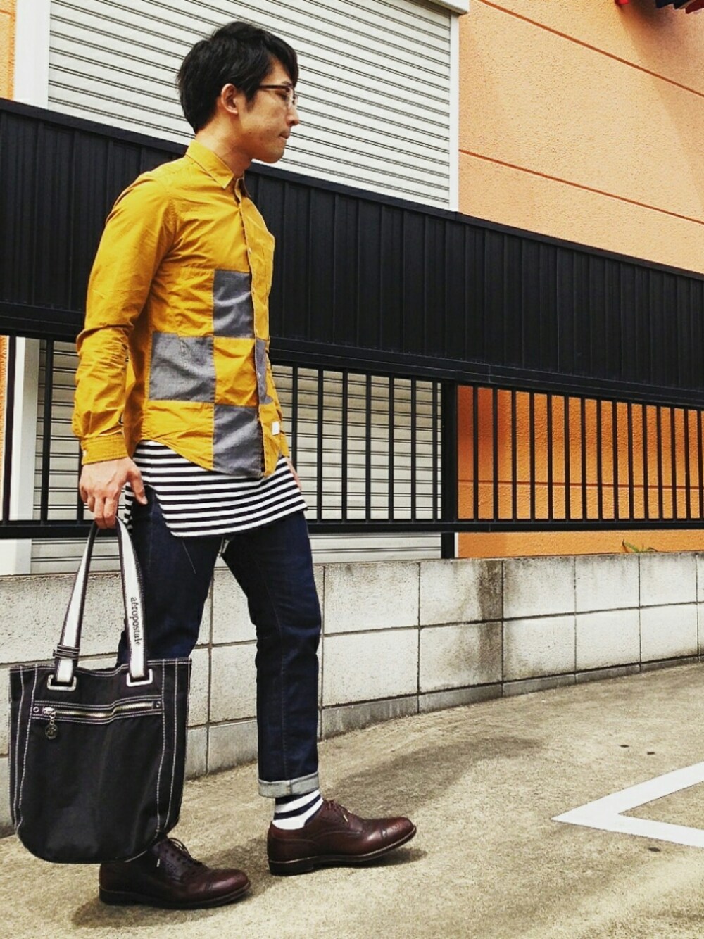 ブラウン系のシューズ、ブルー系のデニムパンツ、イエロー系のトップスを着用したメンズの春コーディネートの1枚目の写真