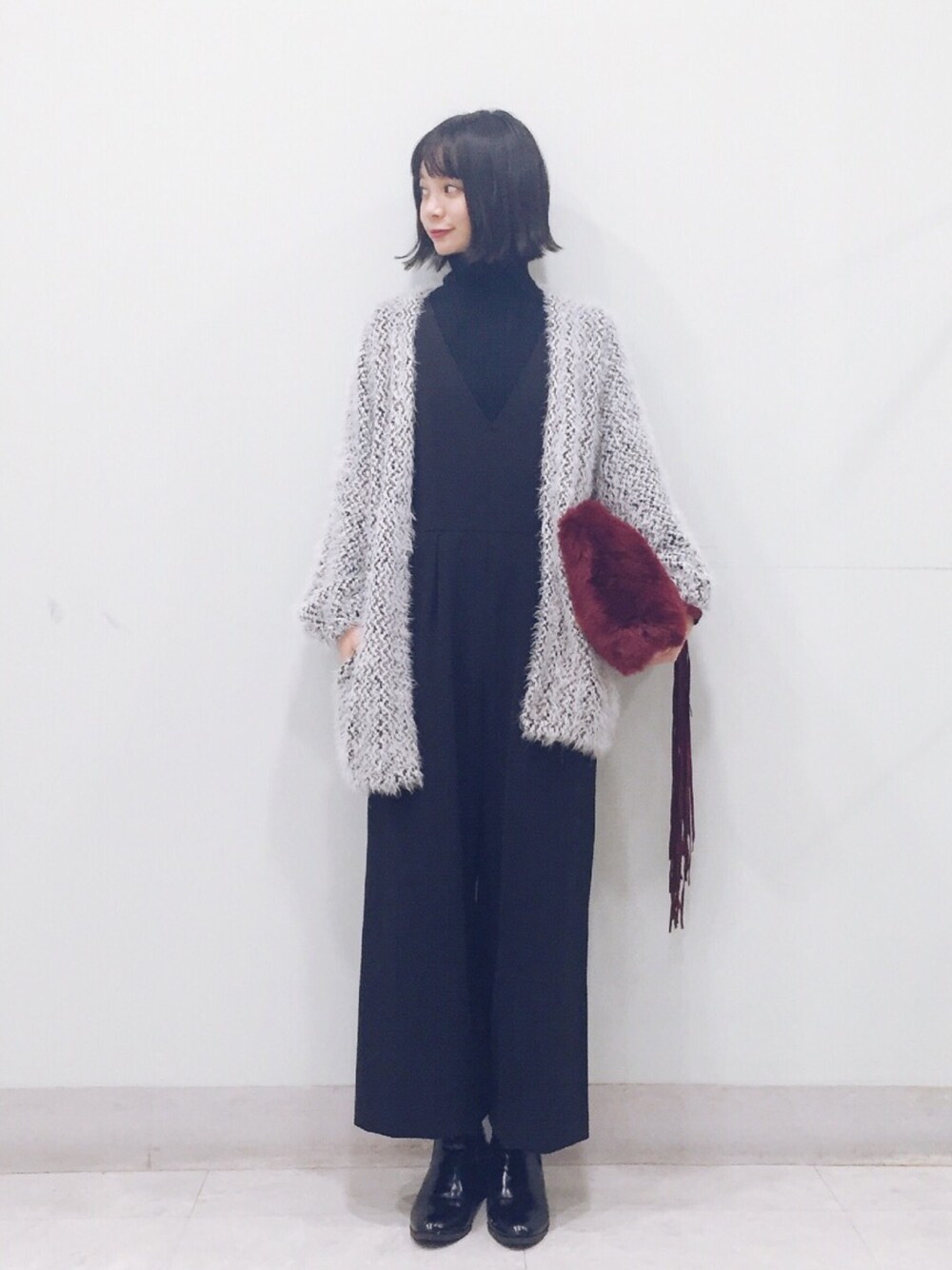 ブラック系のつなぎ/オールインワン、ブラック系のニット/セーター、レッド系のクラッチバッグを着用したレディースの冬コーディネートの1枚目の写真