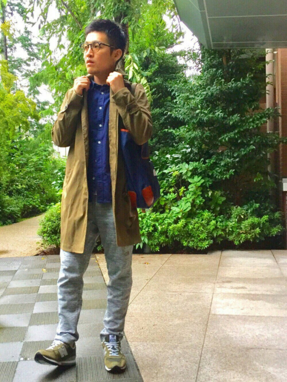 グリーン系のステンカラーコート、グレー系のその他パンツ、グリーン系のスニーカーを着用したメンズの秋コーディネートの1枚目の写真